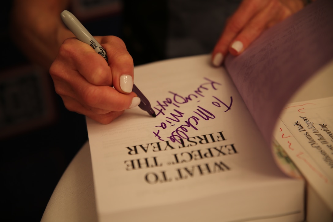 Heidi Murkoff writes a note and signs her book during a Special Delivery baby shower June 17 at the Kadena Officers’ Club on Kadena Air Base. The event helped launch the new Special Delivery Program, in which the USO and the What to Expect Foundation host baby showers at military installations worldwide. Murkoff signed books for expectant mothers at the event. Murkoff is the What to Expect Foundation president and author of a popular book series, which provides information on the different stages of pregnancy and child development. (U.S. Marine Corps photo by Lance Cpl. Devon Tindle/Released)