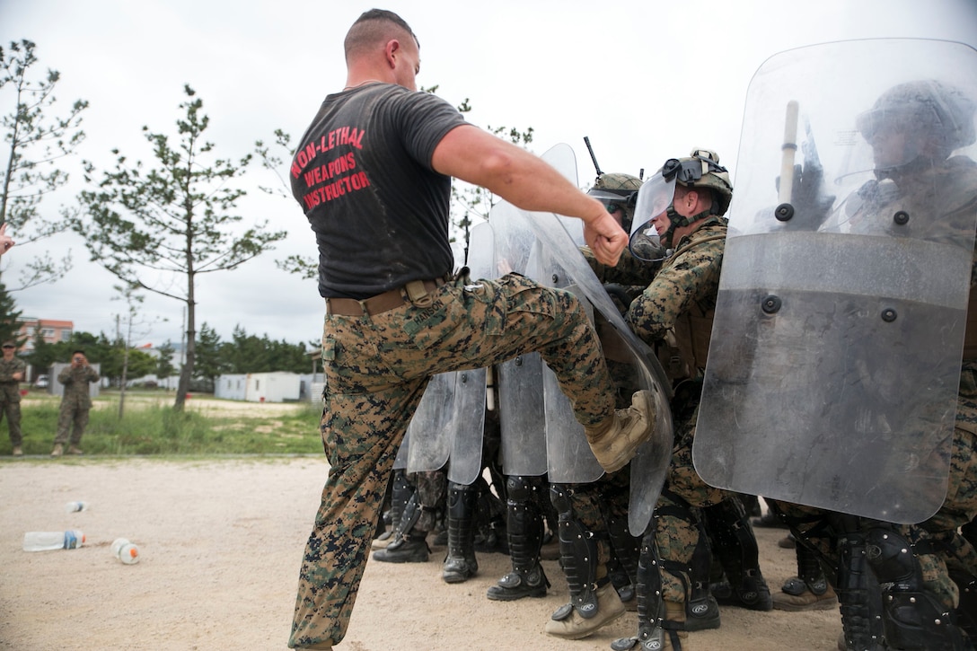 U.S. Marine Staff Sgt. Timothy P. Hanson kicks the riot shield of U.S. Marines and Republic of Korea soldiers June 20 during integrated non-lethal weapons training as part of Korean Marine Exchange Program 14-8 at the 1st Republic of Korea Marine Division base in Pohang. U.S. Marines and ROK soldiers executed the training to improve their crowd control tactics. KMEP 14-8 is a combined, small-unit training exercise, which enhances the combat readiness and interoperability of ROK and U.S. military forces. The exercise familiarizes U.S. Marines with the Korean Peninsula and strengthens the existing relationship between ROK and U.S. Marines. Hanson is a Liverpool, New York, native, correctional specialist and non-lethal weapons instructor with 3rd Law Enforcement Battalion, III Marine Expeditionary Force Headquarters Group, III MEF. The ROK Army soldiers are with Military Police Company, 2nd Operational Command. (U.S. Marine Corps photo by Lance Cpl. Drew Tech/Released)