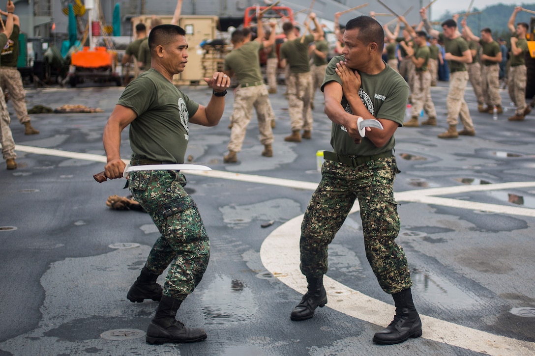 Philippine Tech Sgt. Ernesto Elijan Jr., martial arts instructor assigned to Marine Training Exercise Unit left, and Tech Sgt. Regnante demonstrate proper blade handling techniques to U.S. Marines assigned to Bravo Company, 1st Battalion, 8th Marine Regiment, during Cooperation Afloat Readiness and Training Philippines 2014.  In its 20th year, CARAT is an annual, bilateral exercise series with the U.S. Navy, U.S. Marine Corps and the armed forces of nine partner nations including Bangladesh, Brunei, Cambodia, Indonesia, Malaysia, the Philippines, Singapore, Thailand and Timor-Leste.  