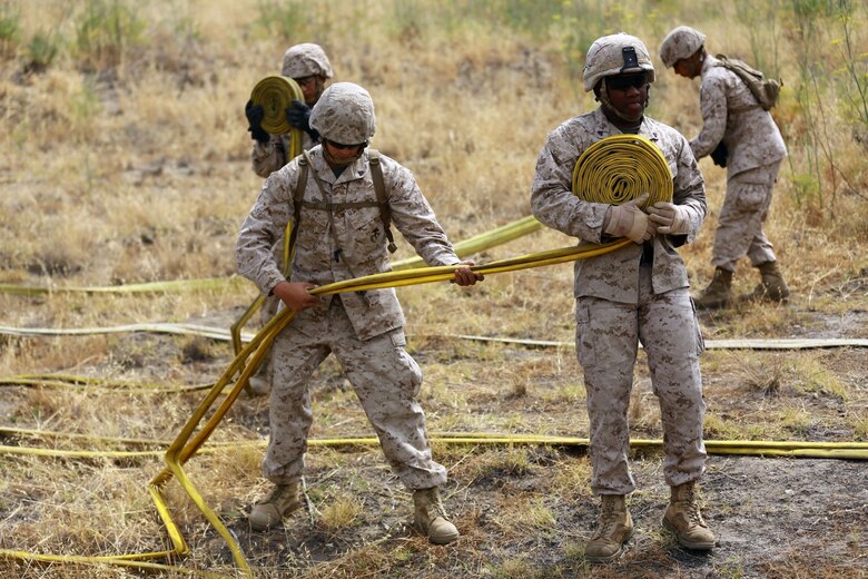 Marines with 2nd Battalion, 11th Marine Regiment, 1st Marine Division, I Marine Expeditionary Force, re-roll hoses during a Woodland Firefighting Course aboard Marine Corps Base Camp Pendleton, Calif., June 26, 2014. The weeklong training was led by firefighters from the California Department of Forestry and Fire Protection and the Camp Pendleton Fire Department. (U.S. Marine Corps Photo by Lance Cpl. Tony Simmons)