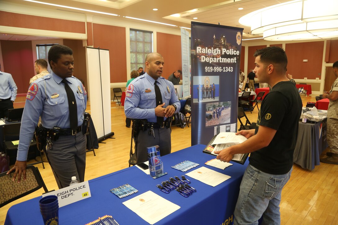 Representatives from the Raleigh Police Department provide an attendee with future job opportunities at the National Vocational and Technical Career Hiring Expo at Marston Pavilion aboard Marine Corps Base Camp Lejeune, June 19. Approximately 60 companies and 500 job seekers attended the expo for education information and job openings.