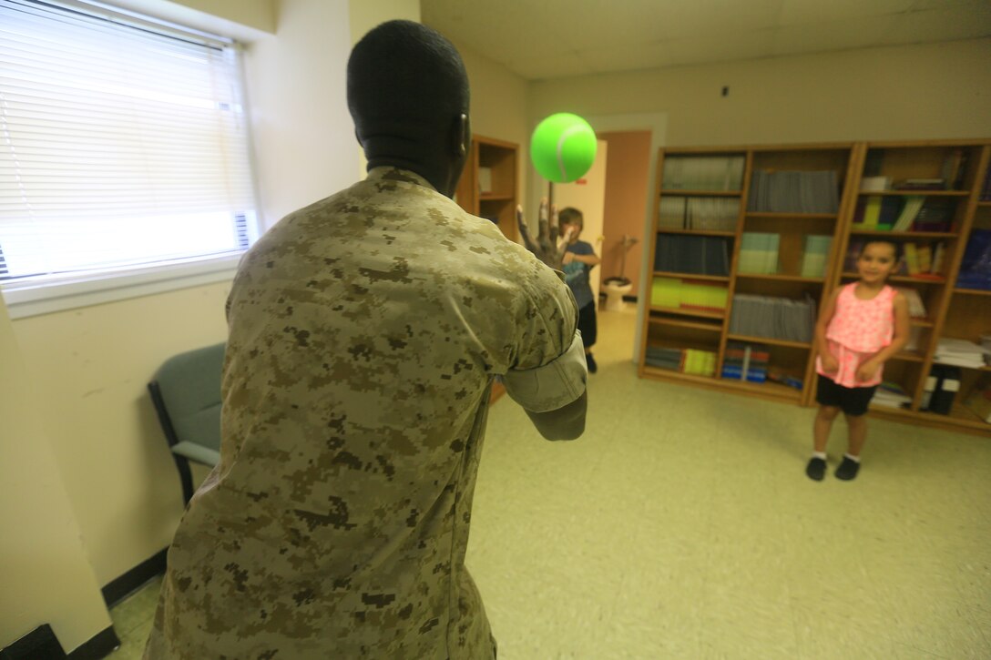 Pfc. Devonte Holmes, a maintenaence clerk with Marine Operational Test and Evaluation Squadron 22, plays catch with children enrolled in the While We Wait Club aboard marine Corps Air Station New River, June 20.
