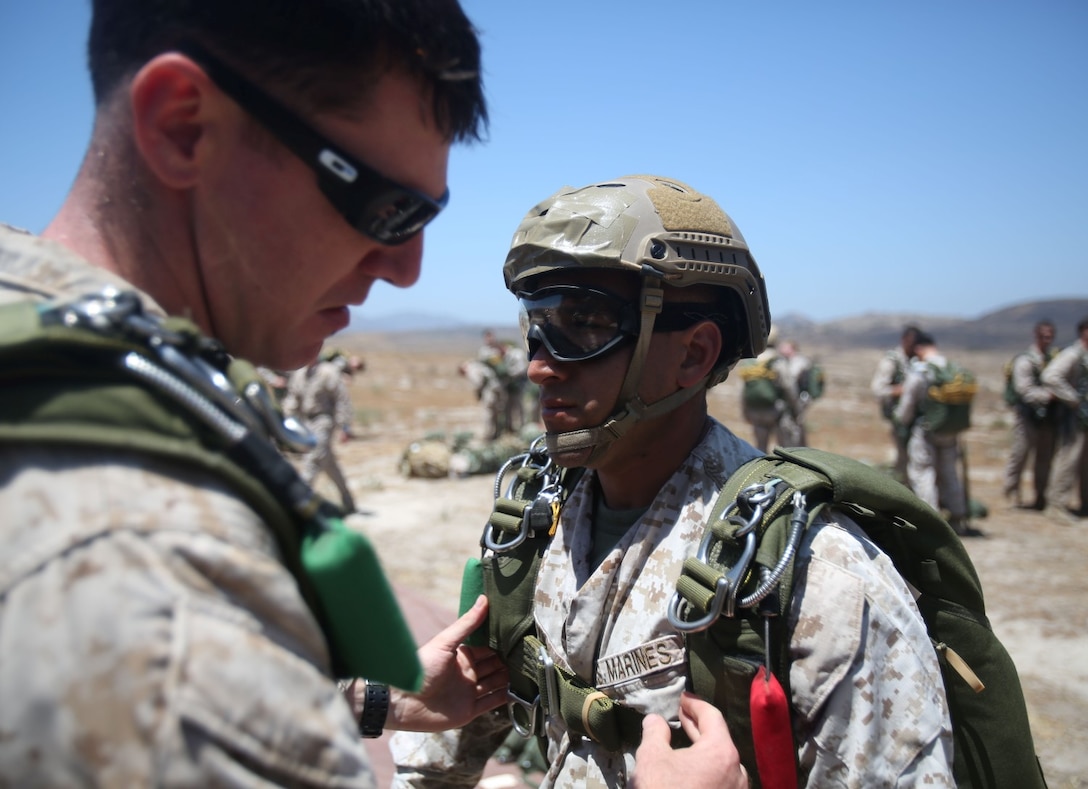 Marines with Company C, 1st Reconnaissance Battalion, prepare for a freefall jump by checking over each other's parachutes several times before boarding the aircraft aboard Marine Corps Base Camp Pendleton, Calif., June 25, 2014. The company practiced both freefall and static line jumps from a CH-46E helicopter to better prepare for potential combat operations anywhere they are needed worldwide.