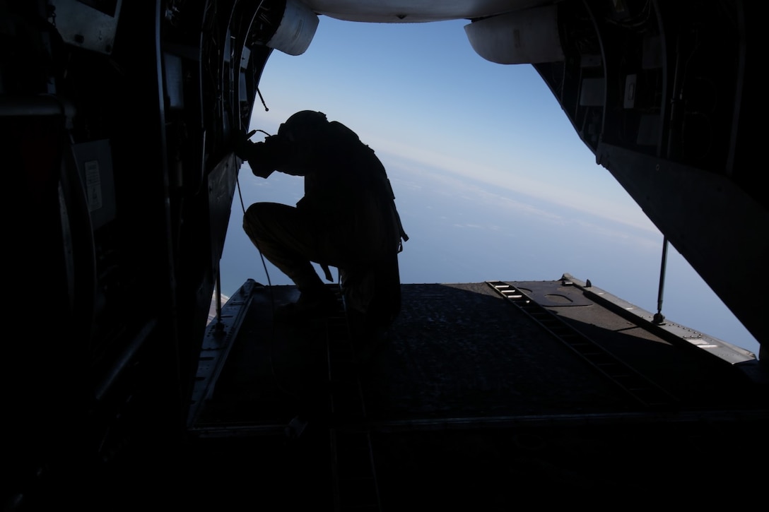 A Marine with Company C, 1st Reconnaissance Battalion, watches from 10,000 feet up as his fellow Marines descend toward their target landing zone during a freefall jump aboard Marine Corps Base Camp Pendleton, Calif., June 25, 2014. The company practiced both freefall and static line jumps from a CH-43E helicopter to better prepare for potential combat operations anywhere they are needed worldwide.