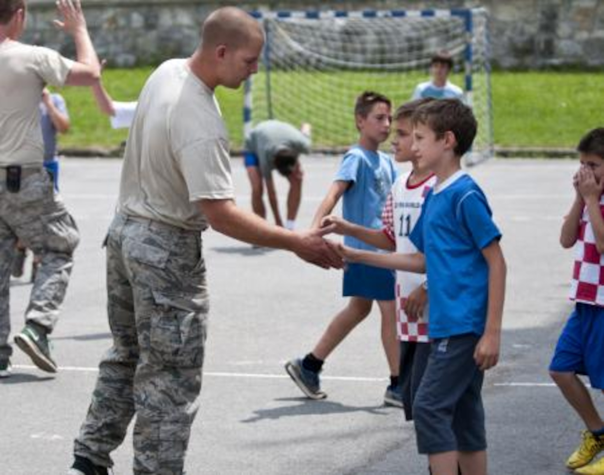 Staff Sgt. Jake Pudlick slaps hands with kids after a brief soccer game outside an elementary school in Ogulin, Croatia, June 18, 2014. The school bathrooms are being renovated by Airmen from the 133rd Civil Engineering Squadron, 148th Civil Engineering Squadron, and 219th Red Horse Squadron in partnership with the Croatian Army. (U.S. Air National Guard photo by Staff Sgt. Austen Adriaens)