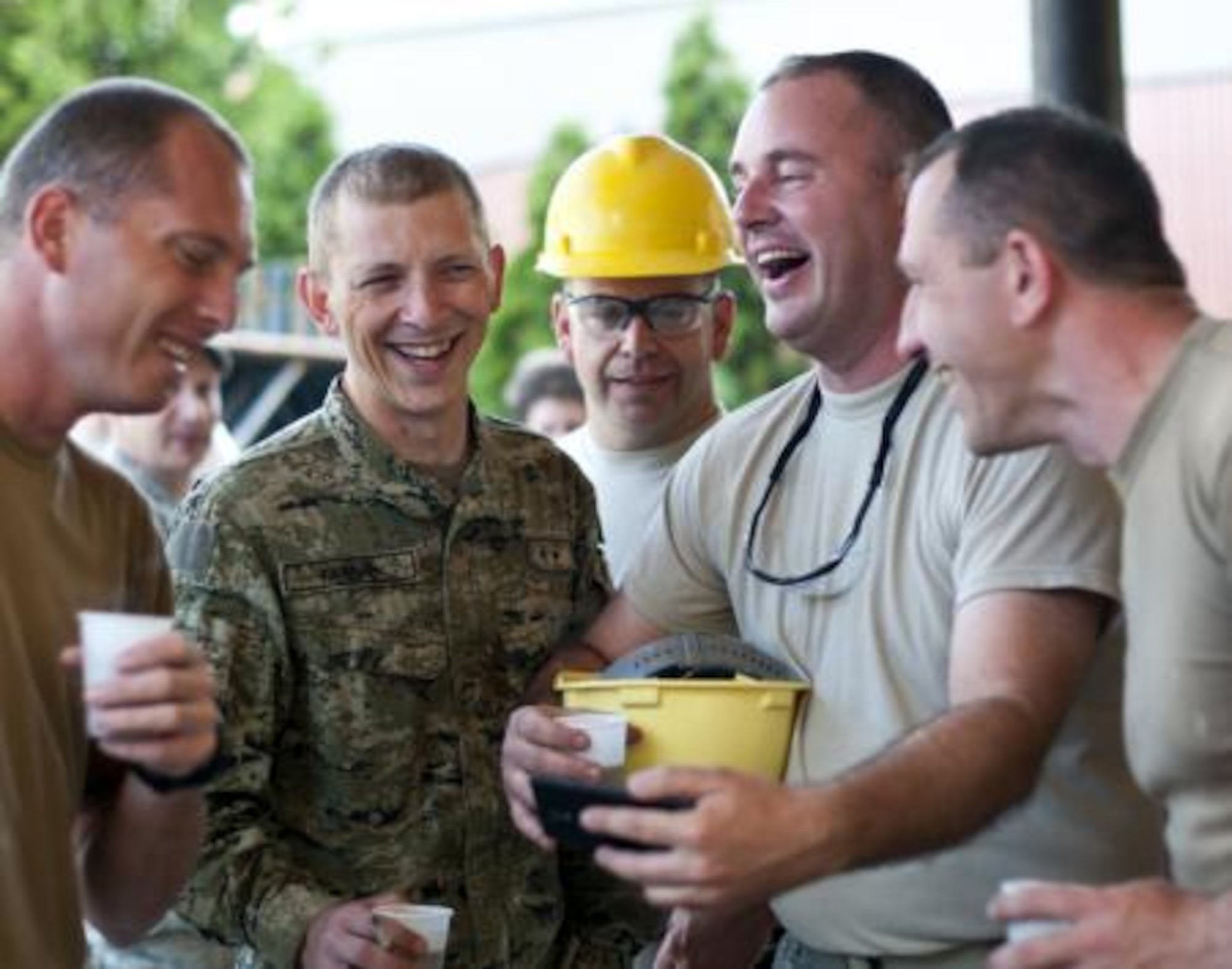 Senior Master Sgt. Kurt Huver, 133rd Civil Engineering Squadron, shares videos on his cellphone with members of the Croatian Army outside an elementary school in Ogulin, Croatia, June 18, 2014. The school bathrooms are being renovated by Airmen from the 133rd Civil Engineering Squadron, 148th Civil Engineering Squadron, and 219th Red Horse Squadron in partnership with the Croatian Army. (U.S. Air National Guard photo by Staff Sgt. Austen Adriaens)