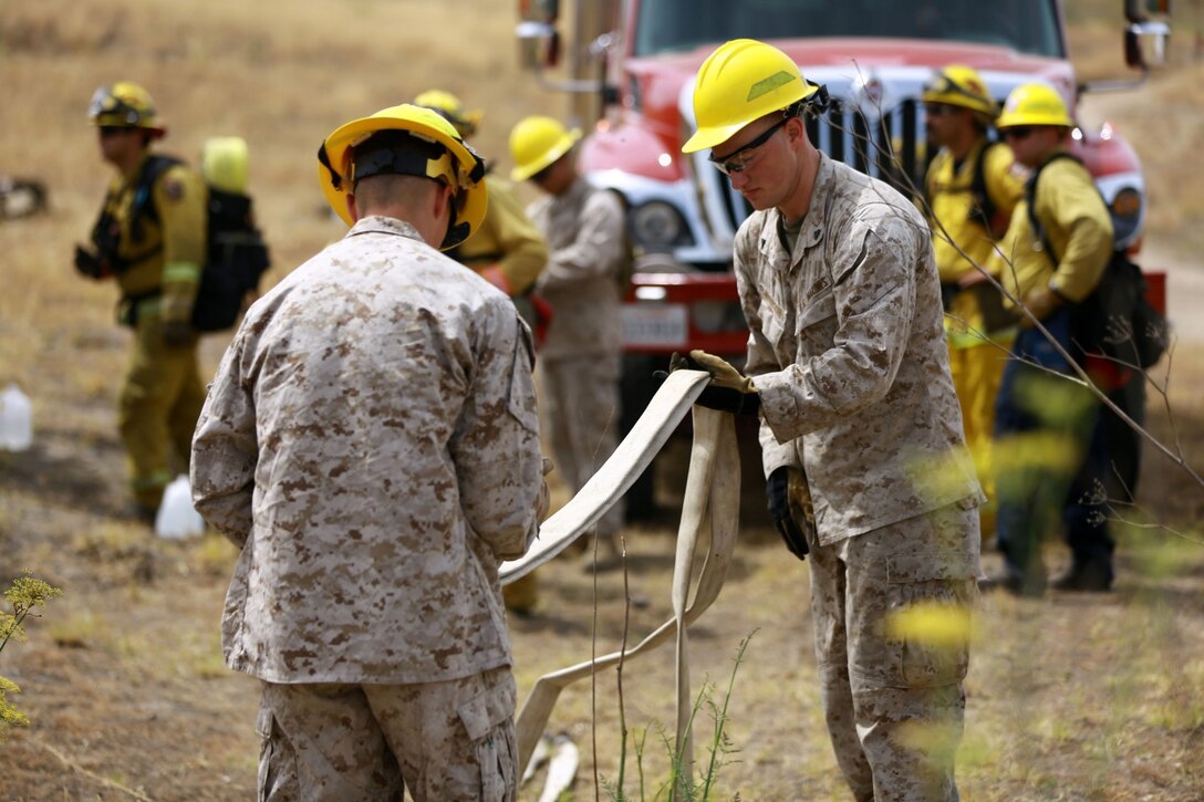 Marines with 2nd Battalion, 11th Marine Regiment, 1st Marine Division, I Marine Expeditionary Force, re-roll hoses during a Woodland Firefighting Course aboard Marine Corps Base Camp Pendleton, Calif., June 26, 2014. The weeklong training was led by firefighters from the California Department of Forestry and Fire Protection and the Camp Pendleton Fire Department. (U.S. Marine Corps Photo by Lance Cpl. Tony Simmons)