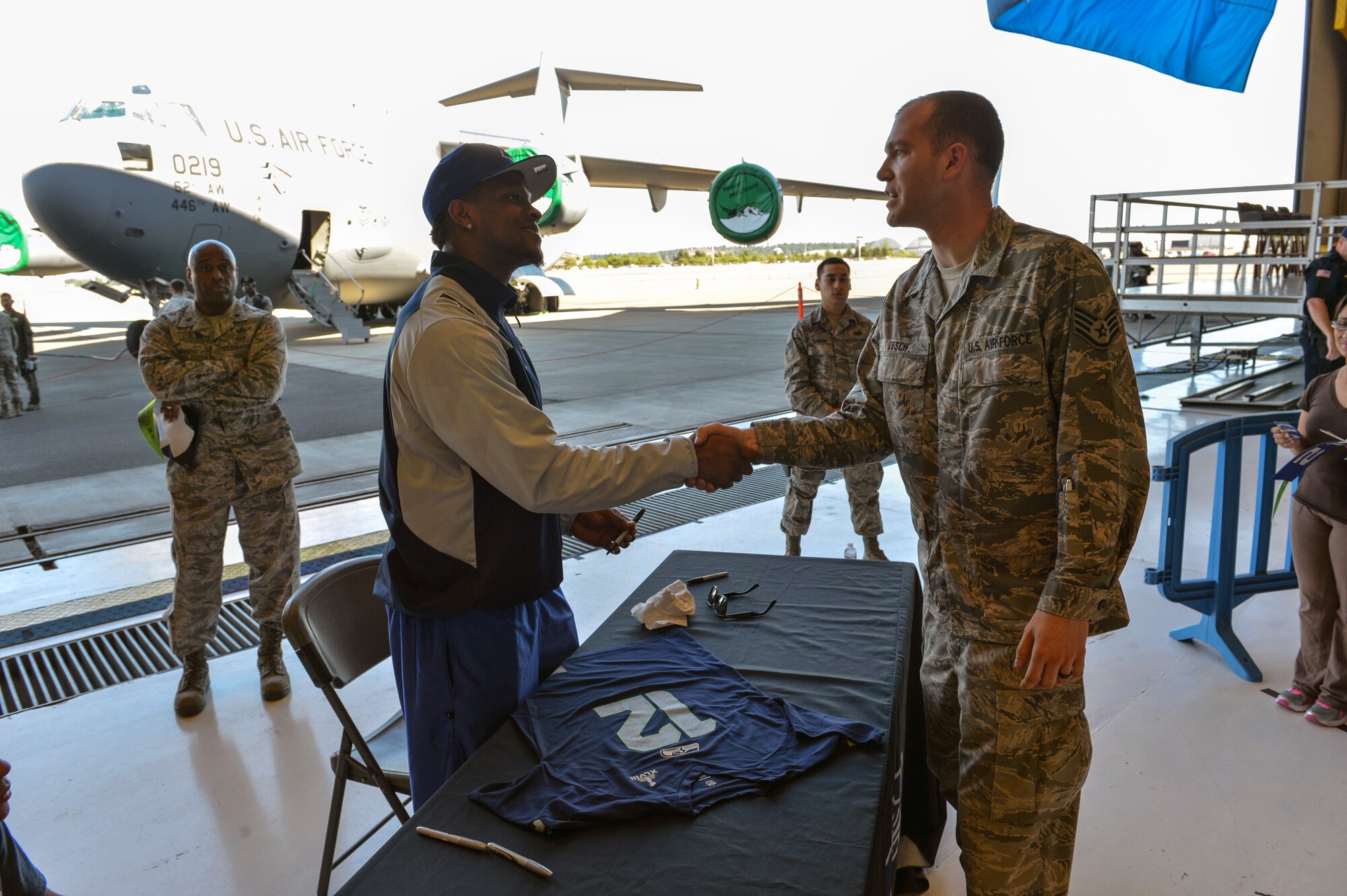 Phil Bates (left), Seattle Seahawks wide receiver, thanks Staff Sgt. Ramsey Tesch (right), for his military service July 1, 2014, after signing a shirt for his Airman Leadership School during the 2014 Seattle Seahawks 12 Tour at Joint Base Lewis-McChord, Wash. Bates is part of the 12 Tour traveling through the Pacific Northwest thanking fans for their support during the championship season. (U.S. Air Force photo/Staff Sgt. Russ Jackson)
