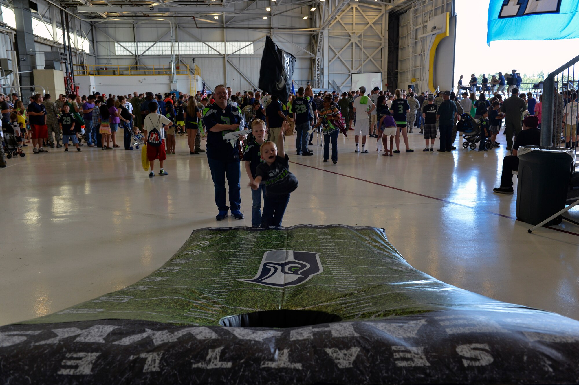 A young Seattle Seahawks fan throws an oversized bean bag July 1, 2014, during the 2014 Seattle Seahawks 12 Tour at Joint Base Lewis-McChord, Wash. The tour’s entertainment featured the Vince Lombardi Trophy, autographs from players, various games, picture opportunities, and performances from the Sea Gals, Blitz the mascot, and the Blue Thunder drum line band. (U.S. Air Force photo/Staff Sgt. Russ Jackson)