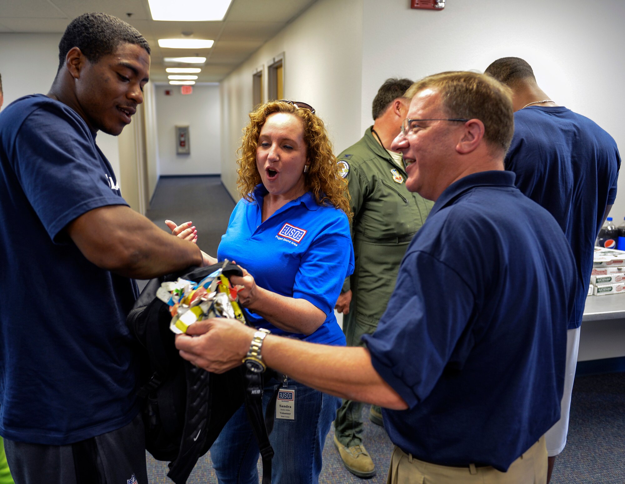 DeShawn Shead (left) Seattle Seahawks cornerback, shows Sandra Miller, USO volunteer and Andrew Oczkewicz (right), USO NW Shali center manager, his bag with airport luggage tags to every city where he has played a game for the Seahawks July 1, 2014, during the 2014 Seattle Seahawks 12 Tour at Joint Base Lewis-McChord, Wash. Shead is part of the 12 Tour taking the Vince Lombardi Trophy through the Pacific Northwest this summer. (U.S. Air Force photo/Staff Sgt. Russ Jackson)