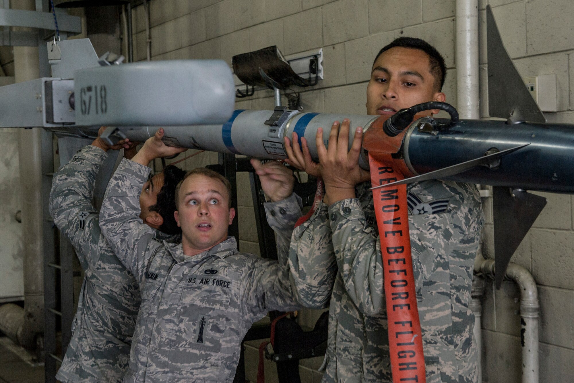 U.S. Air Force Airman 1st Class Christopher Rosadd, Staff Sgt. Jason Macklin, and Senior Airman Zachary Salazar, 354th Aircraft Maintenance Squadron, secure an AIM-9 Sidewinder missile during a load crew competition June 30, 2014, Eielson Air Force Base, Alaska. Points are awarded during the weapons loading, tool kit inspection and uniform inspection for the competition. (U.S. Air Force photo by Senior Airman Joshua Turner/Released)