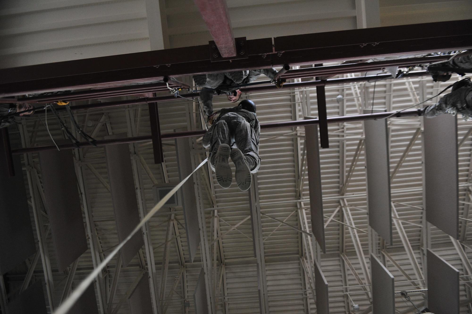 A student attending the Survival, Evasion, Resistance and Escape school hangs off the edge of the second floor in the parachute training center waiting to practice static line rappelling at Fairchild Air Force Base, Washington, June 27, 2014.  The 22nd Training Squadron parachute training tests, evaluates, demonstrates and instructs emergency egress parachute systems for Air Force aircrew career fields. (U.S. Air Force photo by Staff Sgt. Alexandre Montes/Released)