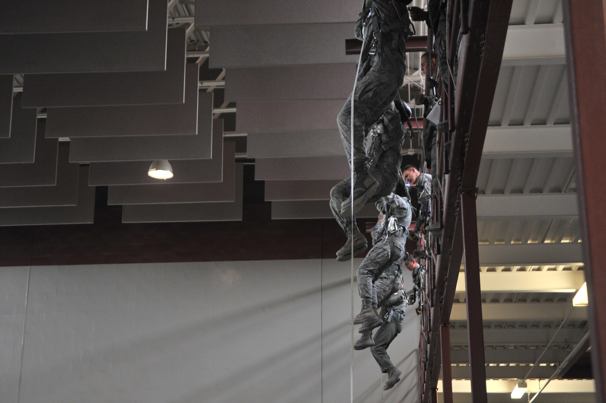 Students attending the Survival, Evasion, Resistance and Escape school hang off the edge of the second floor in the parachute training center to practice static line rappelling at Fairchild Air Force Base, Washington, June 27, 2014.  The 22nd Training Squadron parachute training tests, evaluates, demonstrates and instructs emergency egress parachute systems for Air Force aircrew career fields. (U.S. Air Force photo by Staff Sgt. Alexandre Montes/Released)