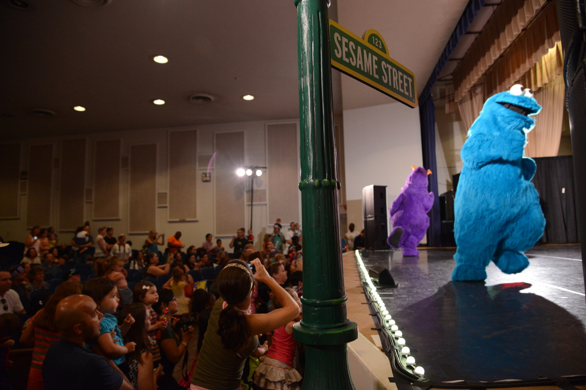 PETERSON AIR FORCE BASE, Colo. – Muppets sing and dance while Team Pete kids participate in a Muppet mosh pit during the Sesame Street USO experience for military families at the base auditorium June 28. The show is about Katie, a military child and Muppet, who is moving from Sesame Street to a new base. Through song and dance, the rest of the Muppets show her that moving is not so bad. (U.S. Air Force photo/Tech. Sgt. Jared Marquis)