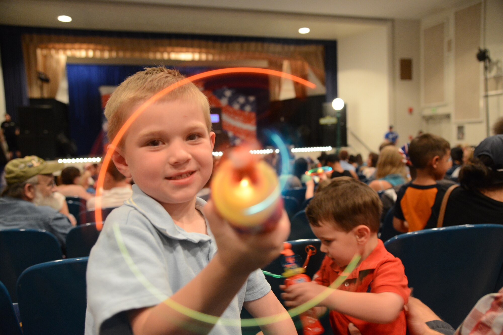 PETERSON AIR FORCE BASE, Colo. – Wyatt McClain (left), and his brother Dustin McClain wait for the Sesame Street USO experience for military families to begin at the base auditorium June 28. The staff and volunteers handed out spinners and bandanas for kids attending the performance. The show is about Katie, a military child and Muppet, who is moving from Sesame Street to a new base. Through song and dance, the rest of the Muppets show her that moving is not so bad. (U.S. Air Force photo/Tech. Sgt. Jared Marquis)