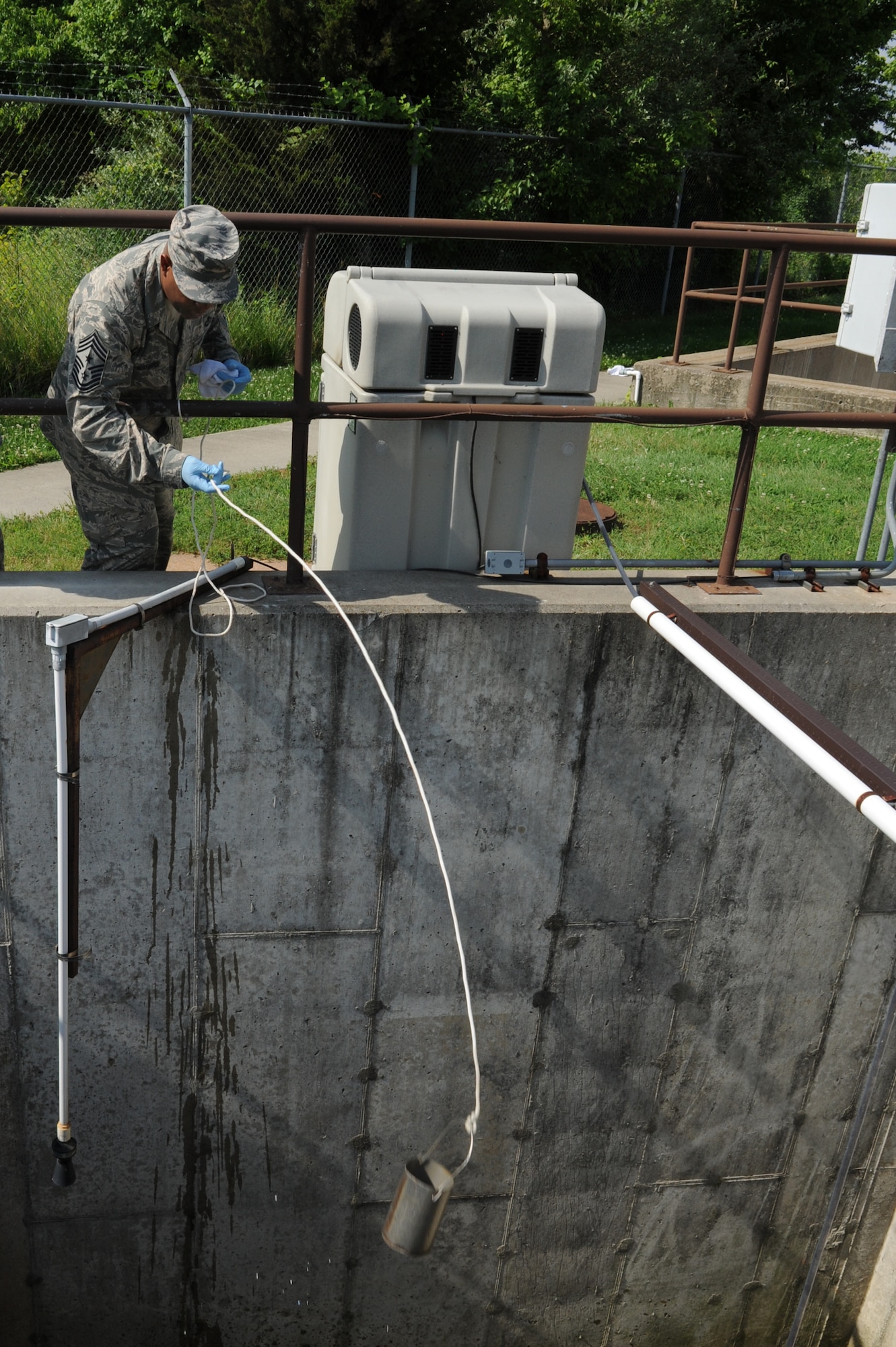 Chief Master Sgt. Wesley Mathias, 375th Air Mobility Wing command chief, collects a sample of water at the waste water treatment plant at Scott Air Force Base, Ill. on June 23, 2014. The plant cleans and treats waste water and the base reuses it to irrigate the golf course and other base locations. (U.S. Air Force photo by Senior Airman Sarah Hall-Kirchner/Released)