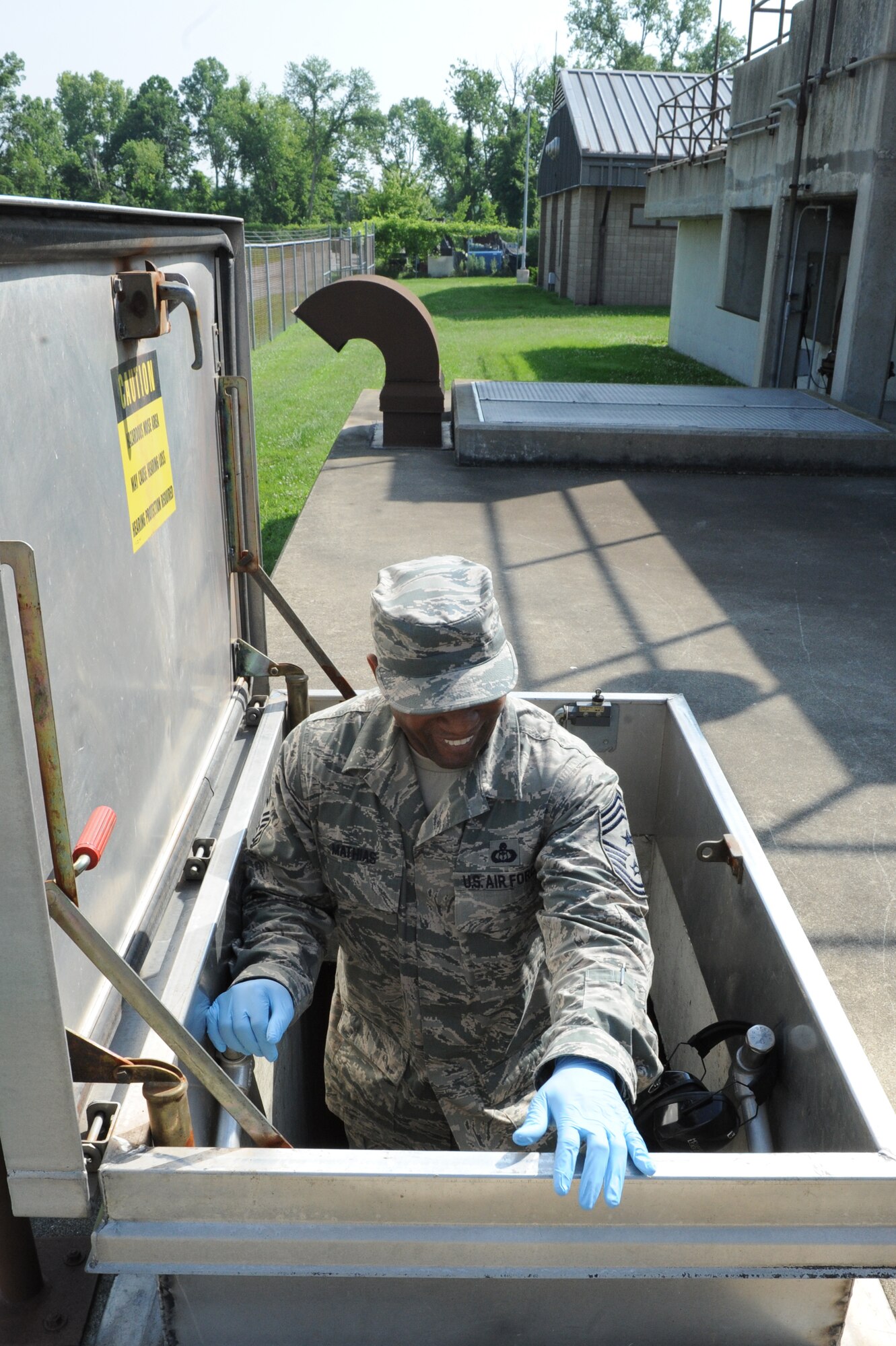 Chief Master Sgt. Wesley Mathias, 375th Air Mobility Wing command chief, descends into a section of the waste water treatment plant at Scott Air Force Base, Ill. on June 23, 2014 to collect a water sample. The plant cleans and treats waste water and the base reuses it to irrigate the golf course and other base locations. (U.S. Air Force photo by Senior Airman Sarah Hall-Kirchner/Released)