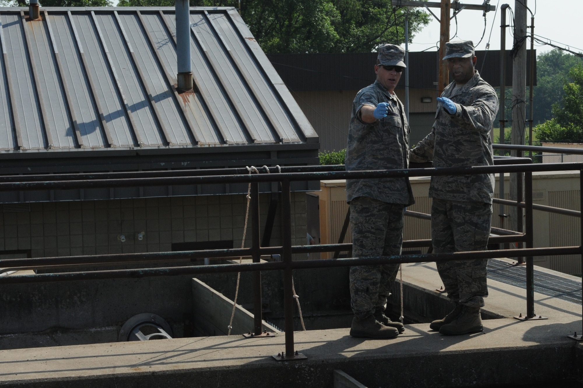 Chief Master Sgt. Wesley Mathias, 375th Air Mobility Wing command chief, talks with Senior Airman Bryan Richardson, 375th Civil Engineer Squadron water and fuels systems maintenance journeyman, about how one step in the process works at the waste water treatment plant at Scott Air Force Base, Ill. on June 23, 2014. The plant cleans and treats waste water using a multi-step process and the base reuses it to irrigate the golf course and other base locations. (U.S. Air Force photo by Senior Airman Sarah Hall-Kirchner/Released)
