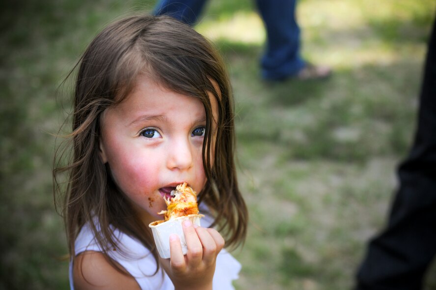 Aislin Ellis, 2-year-old daughter of U.S. Air Force Staff Sgt. Douglas Ellis, enjoys a barbeque-style chicken wing during the Moody Field Club's Barbecue Cook-off June 27, 2014, at Moody Air Force Base, Ga. The event featured 12 grill masters who competed for bragging rights in several categories, to include crowd favorite. (U.S. Air Force photo by Andrea Jenkins)