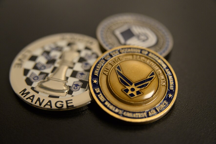 The history of the military challenge coin dates back to World War I when a U.S. pilot was shot down over enemy lines. To show French officers that captured him that he was an ally he presented a medallion with his units’ insignia on it. Instead of executing him, they gave him a bottle of wine. Today, military members play a game using military coins. Members playing the game present the coin when challenged, and whoever produces a lesser coin must purchase the next round of drinks. (U.S. Air Force photo by Airman 1st Class Michael A. Cossaboom/Released)