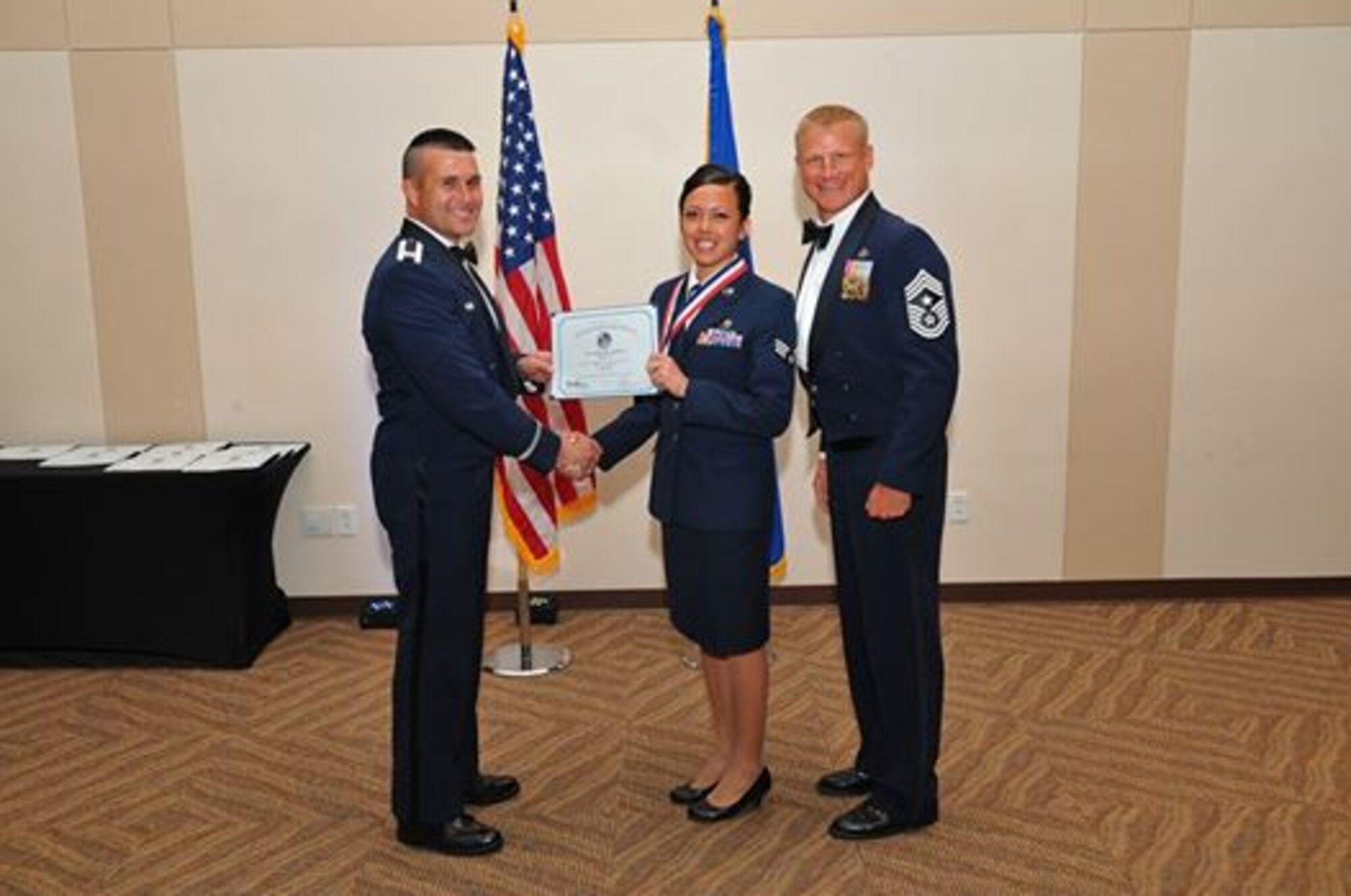 Col. John Wagner, 460th Space Wing commander, and Chief Master Sgt. Craig S. Hall, 460th Space Wing command chief, congratulate Senior Airman Ashley Jalbert during the Airman Leadership School graduation ceremony June 26, 2014, at the Leadership Development Center on Buckley Air Force Base, Colo. This graduation represents an important part of the enlisted force professional military education, teaching valuable skills required for supervisors. (U.S. Air Force photo by Senior Airman Phillip Houk/Released)