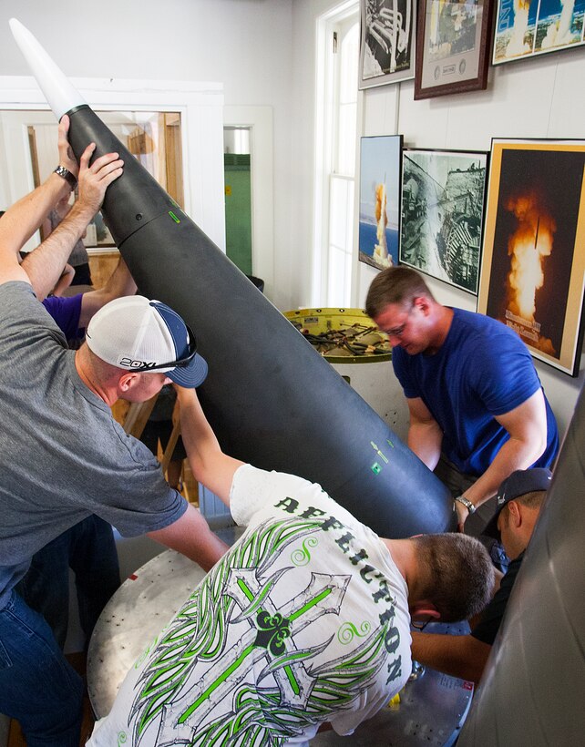 Senior Airman Cody Pollock, 90th Munitions Squadron, puts the final touches on the stencil placed on a Minuteman III shroud in the F.E. Warren ICBM and Heritage Museum June 20, 2014. Airmen from the squadron volunteered on their day off to clean and assemble pieces of the display. (U.S. Air Force photo by R.J. Oriez) 