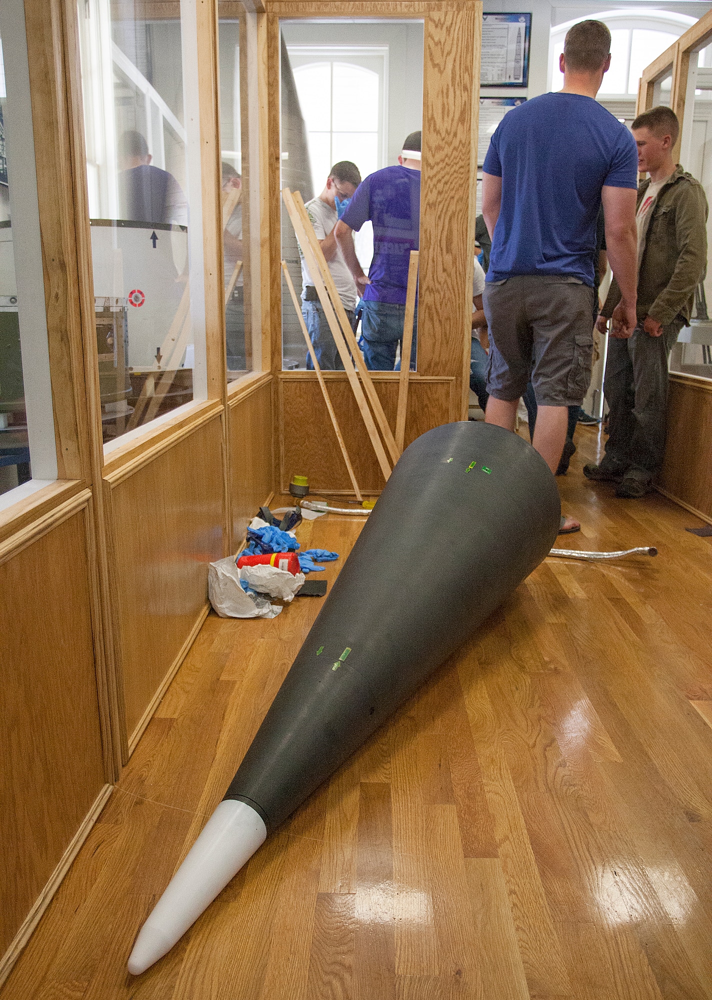 An ICBM re-entry system lies on the floor of the F.E. Warren ICBM and Heritage Museum, June 20, 2014, while Airmen of the 90th Munitions Squadron perform maintenance on the components of the museum’s Minuteman III display. Airmen from the squadron volunteered on their day off to clean and assemble pieces of the display. (U.S. Air Force photo by R.J. Oriez)