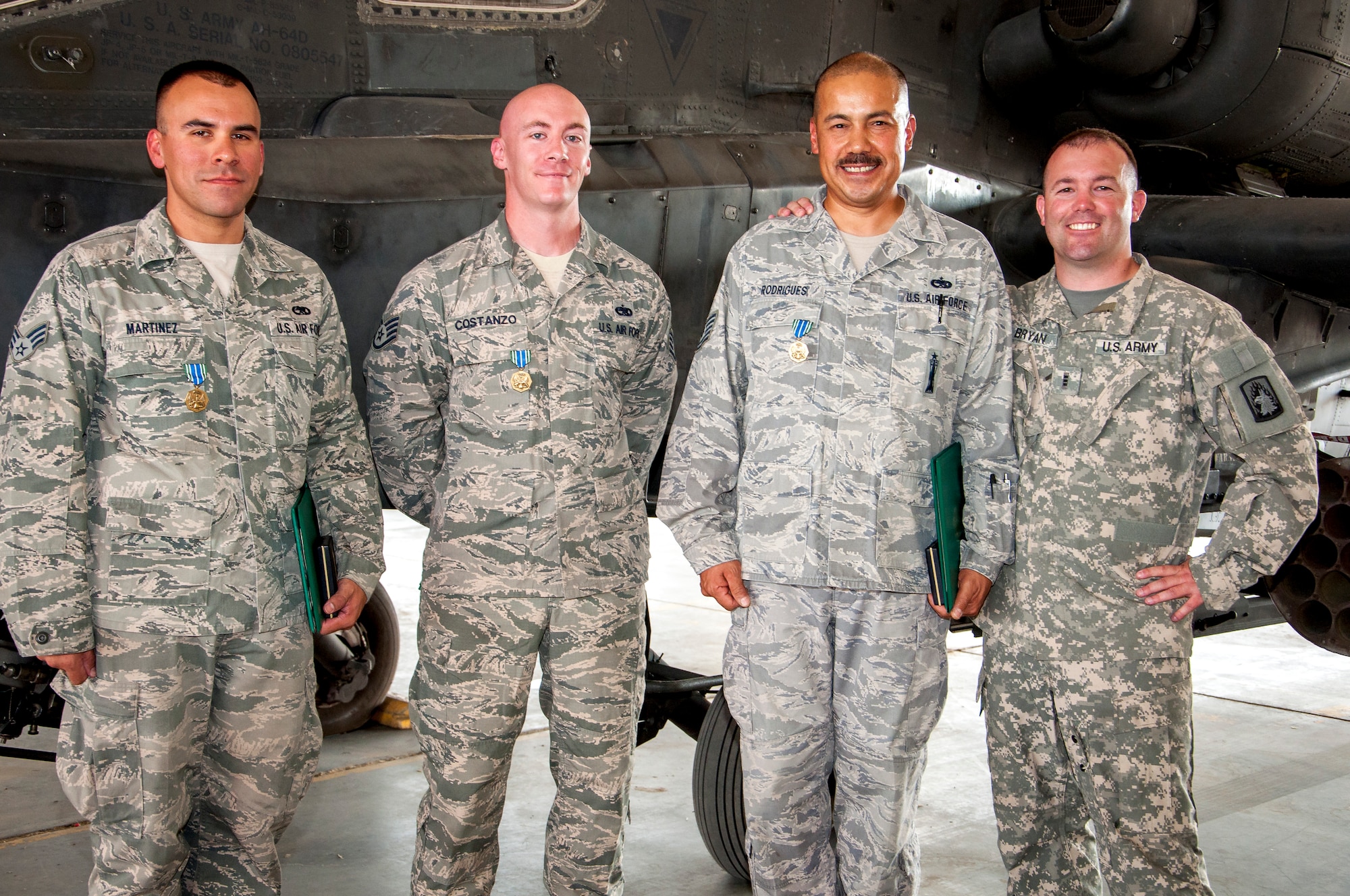 Senior Airman Loren Martinez, Staff Sgt. Justin Costanzo, Tech. Sgt. Abel Rodriguez pose with Army Chief Warrant Officer 3 Shawn Bryan, Bravo Company 3-159th Attack Reconnaissance Battalion test pilot in front of an AH-64D Apache Longbow after he presented them each with an Army Achievement Medal June 28, 2014. The three Air Force Airmen were responsible for structural and composite repairs on a dozen AH-64Ds ensuring the aircraft were mission ready. Rodrigues from La Palma, California; Costanzo from Washingtonville, New York and Martinez from Baldwin Park, California, deployed from the 146th Airlift Wing, Channel Islands Air National Guard Station, California, in support of Operation Enduring Freedom. (U.S. Air Force photo by Senior Master Sgt. Allison Day)