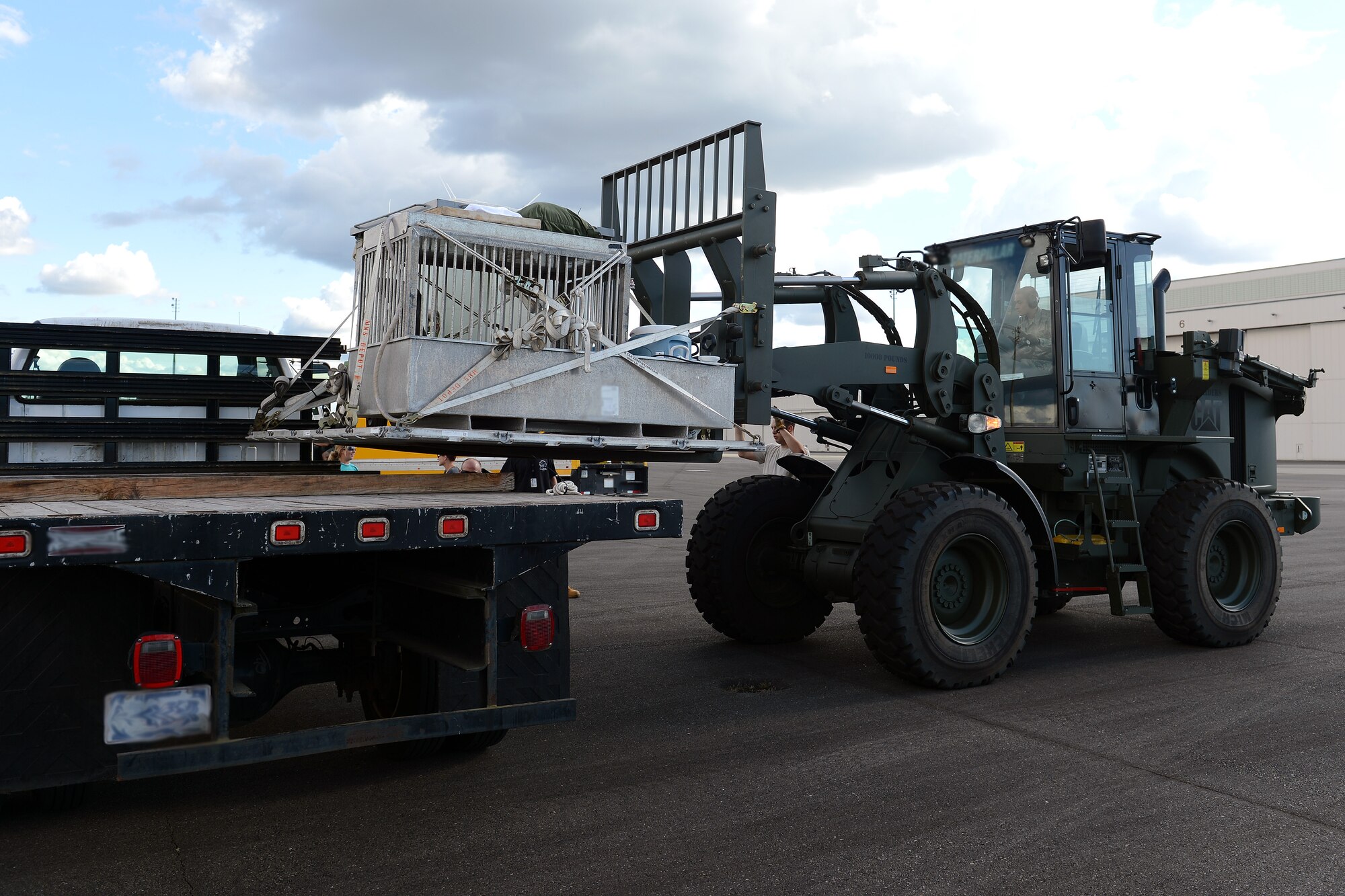 Airman 1st Class Elishah Webb, 62nd Aerial Port ramp services element member, maneuvers a 10k all-terrain forklift while loading a pallet holding a sea lion onto a flatbed truck June 24, 2014 at Joint Base Lewis-McChord, Wash. The sea lion, Sundance, is part of the Navy Marine Mammal Program’s swimmer interdiction security program and is trained to detect and mark the location of objects under water. (U.S. Air Force photo/Airman 1st Class Jacob Jimenez)