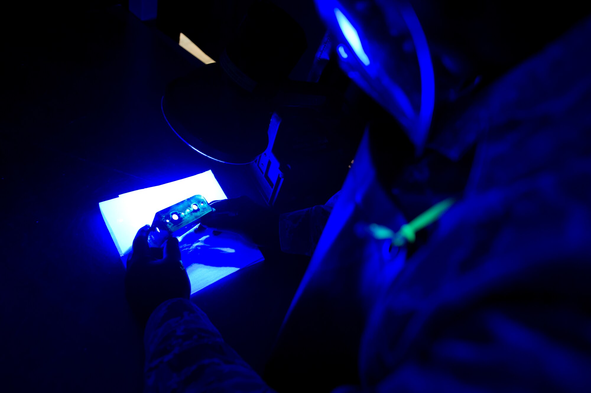 Senior Airman Roderick Johnson, 49th Maintenance Squadron non-destructive inspection technician, inspects a metal bracket coated with fluorescent penetrant at Holloman Air Force Base, N.M., June 30. The item is dipped in a very low viscosity penetrant which fills any voids left by cracks or damage and indicates a need for repair. After the penetrant is applied, it is placed on a surface for a specific period of time to allow the penetrant to create a visible indication of damage under a black light. NDI technicians are able to assist aircraft maintainers by identifying damage to aircraft parts in a non-destructive manner, allowing them to ensure military aviation equipment safety. (U.S. Air Force photo by Airman 1st Class Aaron Montoya / Released)