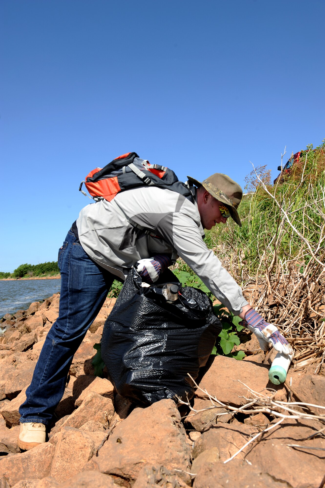 U.S. Air Force Airman 1st Class Ethan Karstetter, 7th Component Maintenance Squadron, Dyess Air Force Base, picks up trash on the banks of Kirby Lake, June 14, 2014, in Abilene Texas. Karstetter, along with more than 30 other Dyess Airmen and family members, spent 4 hours gathering trash and debris from around the lake. (U.S. Air Force photo by Airman 1st Class Alexander Guerrero/Released)