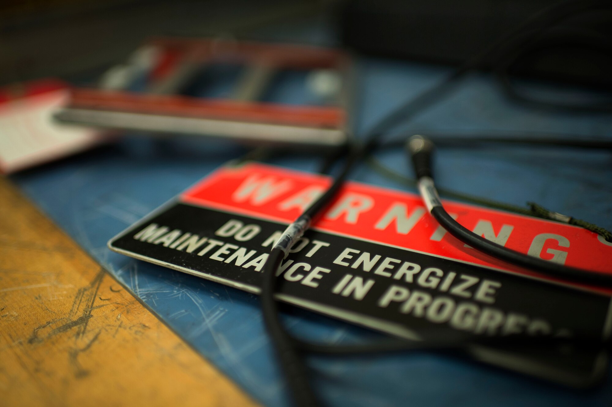 A warning sign rests on the workbench of a radio maintenance bay at Spangdahlem Air Base, Germany, June 30, 2014. Technicians must use proper personal protective gear while performing maintenance to ensure the safety of themselves and the equipment. (U.S. Air Force photo by Senior Airman Gustavo Castillo/Released)