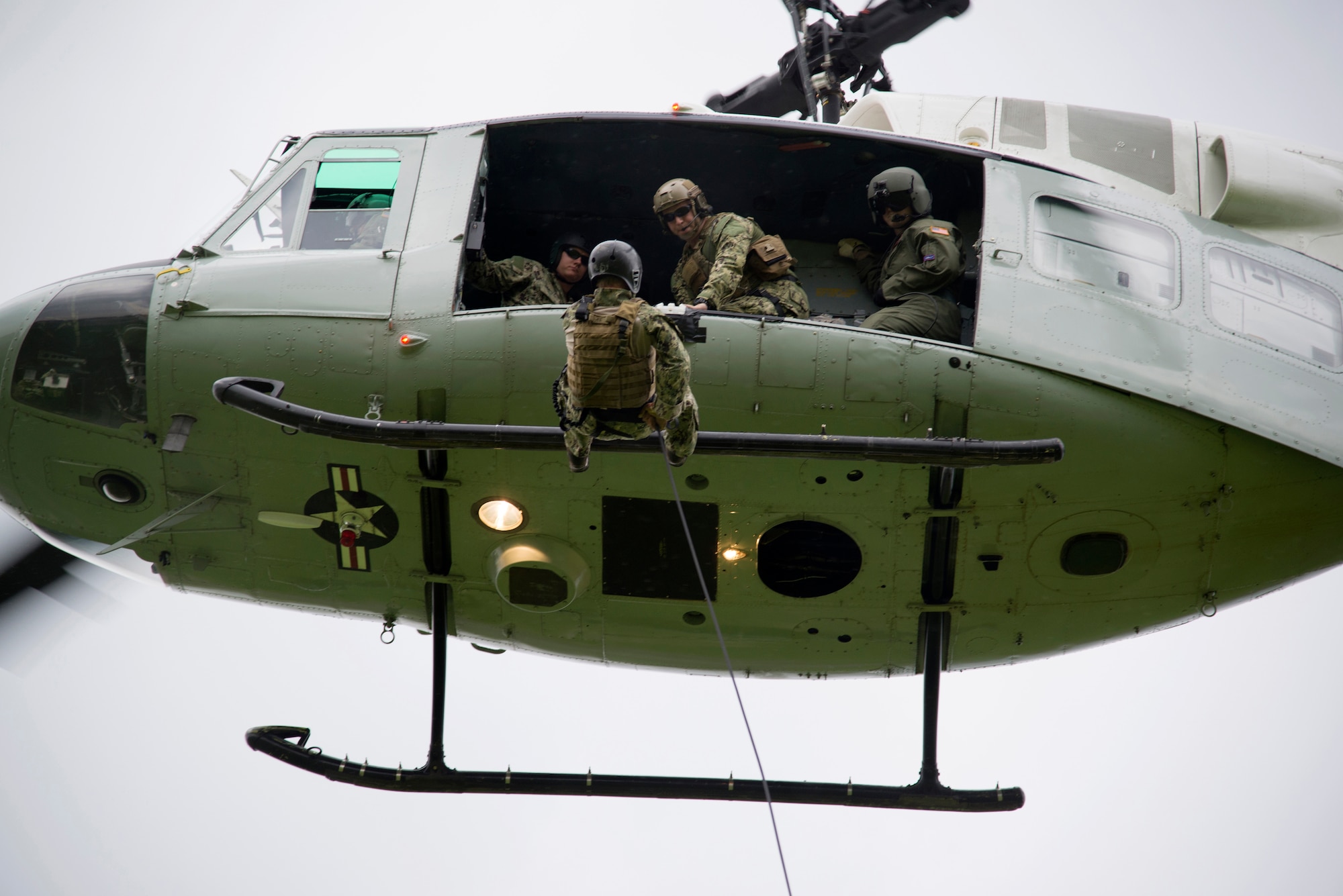 U.S Navy Explosive Ordnance Disposal Technician Senior Chief Mark Morgan, assigned to EOD Mobile Unit 5, Yokosuka Naval Base, Japan, prepares to bound from the skid of a UH-1N Huey during rappel training with the 459th Airlift Squadron June 25, 2014 at Yokota Air Base,  Japan.  The rappels allowed the 459 AS and the Navy EOD team the opportunity to train on alternate personnel insertion and extraction. (U.S. Air Force photo by Tech Sgt. Melissa K. Mekpongsatorn/Released)