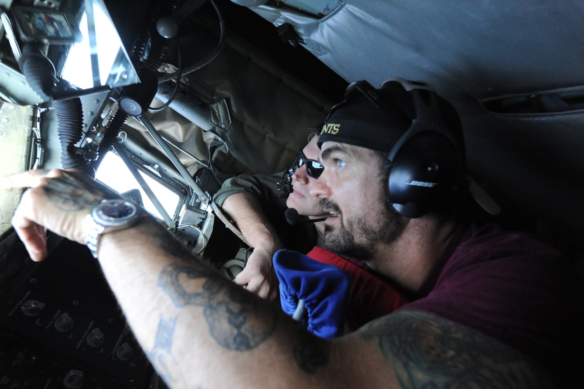 Chris Henderson, 3 Doors Down guitarist, look out the window of a KC-135 Stratotanker boom pod with Staff Sgt. Jeremy Hall, 909th Air Refueling Squadron boom operator, at Kadena Air Base, Japan, June 30, 2014. 3 Doors Down headlined at AmericaFest 2014 both nights and were invited on an air refueling training mission as a "thank you" for their performance. (U.S. Air Force photo by Airman 1st Class Zackary A. Henry)