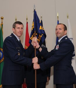 Col. Thomas Kunkel hands the guidon to Lt. Col. Chadwick Sterr during the Joint Personnel Recovery Agency change of command ceremony at the White Bluff Facility in Airway Heights, Washington, July 1, 2014. The change of command ceremony is a tradition that represents a formal transfer of authority and responsibility. Kunkel is the Air Force JPRA deputy director and Sterr is the local JPRA commander. (U.S. Air Force photo by Airman 1st Class Janelle Patiño/Released)