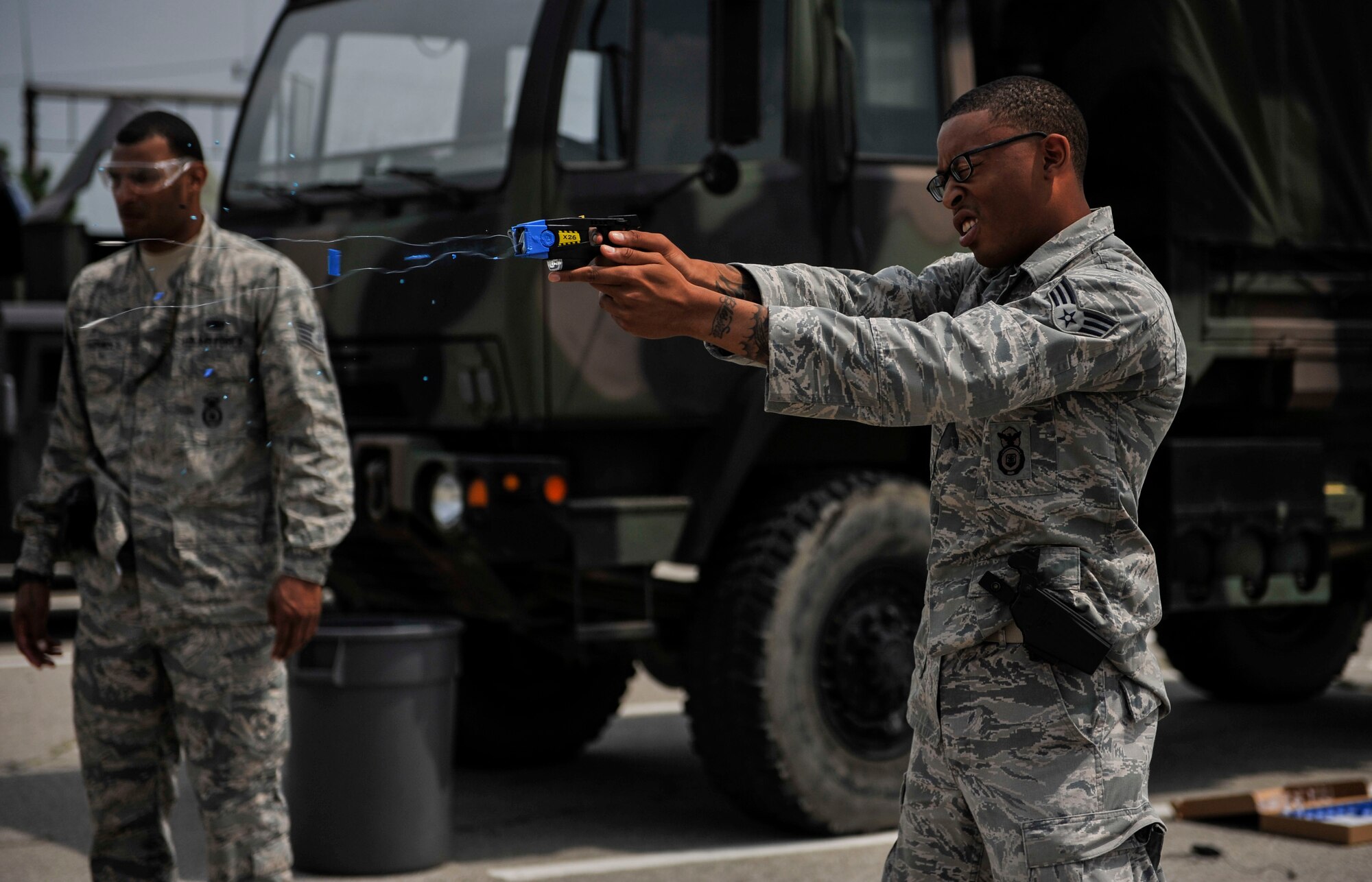 Senior Airman Marcus Thomas, 51st Security Forces Squadron entry controller, fires a Taser during training on Osan Air Base, Republic of Korea, June 27, 2014. The Taser fires two small dart-like electrodes which stay connected to the main unit by conductive wire while being propelled by small compressed nitrogen charges. (U.S. Air Force photo/Senior Airman David Owsianka)