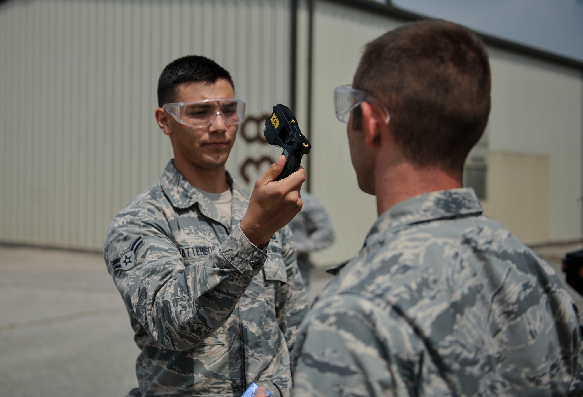 Senior Airman Jeffery Reinke 51st Security Forces Squadron entry controller, holds a Taser as Capt. Tate Grogan, 51st SFS assistant operations officer, inspects it during Taser training on Osan Air Base, Republic of Korea, June 27, 2014. Defenders must effectively engage a target with two Taser cartridges to pass this portion of the training. (U.S. Air Force photo/Senior Airman David Owsianka)