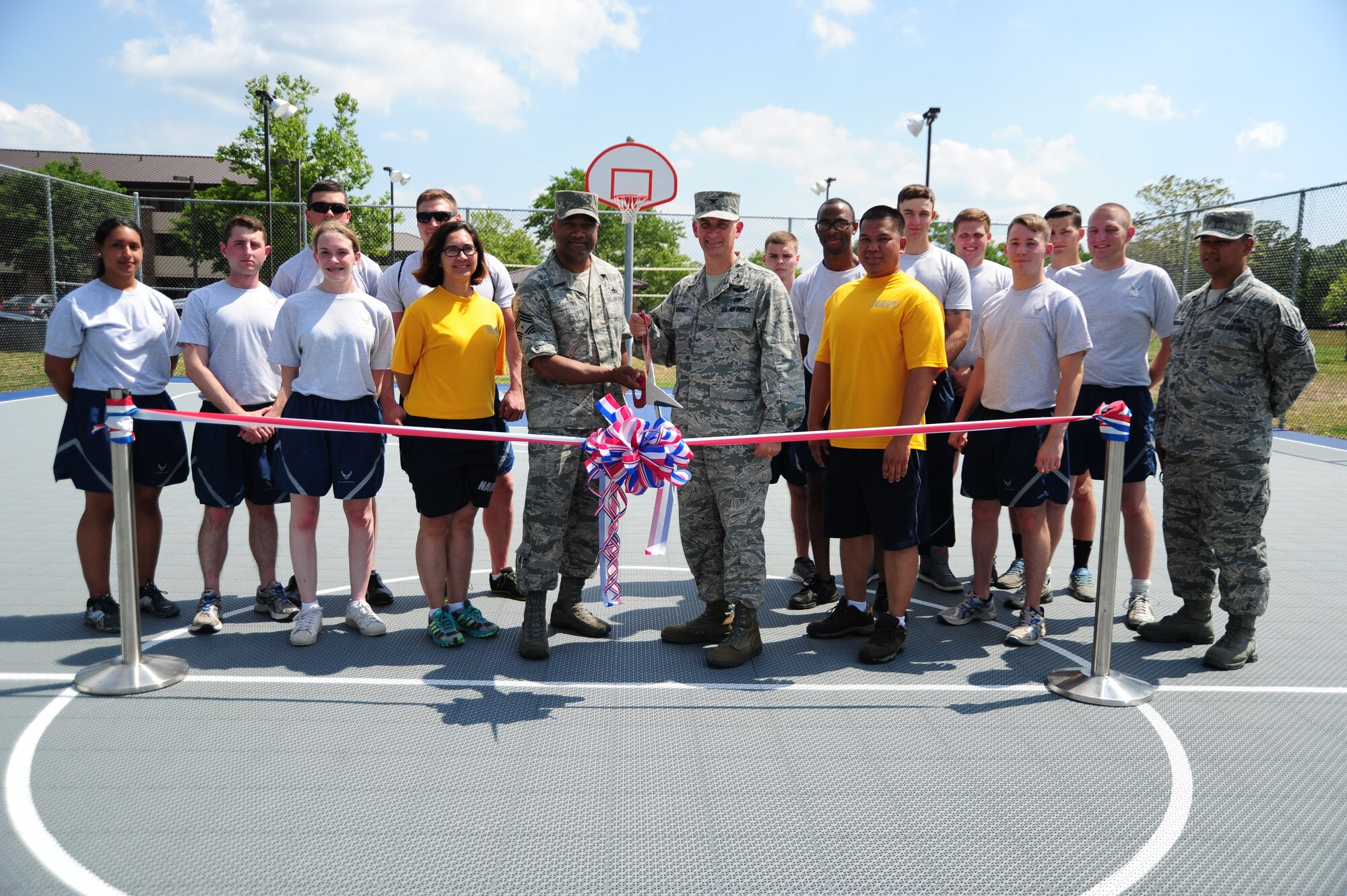 Col. Bill Knight, 11th Wing/Joint Base Andrews commander, and Chief Master Sgt. William Sanders, 11th WG/JBA command chief, pose for a ribbon cutting with dorm residents for official opening of the new volleyball and basketball court at Joint Base Andrews, Md., June 26, 2014. (U.S. Air Force photo/Airman 1st Class Joshua R. M. Dewberry)