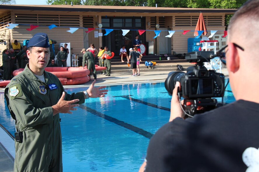 Commander of the 932nd Airlift Wing, Col. Albert Lupenski, talks about upcoming wing training as the 932nd Aeromedical Evacuation Squadron goes through water survival training class at the pool.  At right, Tech. Sgt. Christopher Parr, public affairs specialist and 932nd Unit Public Affairs Representative coach, adjusts his ISO and microphone settings on the camera during an intensive video training moment, followed by six hours of editing work.  (U.S. Air Force photo/Maj. Stan Paregien)