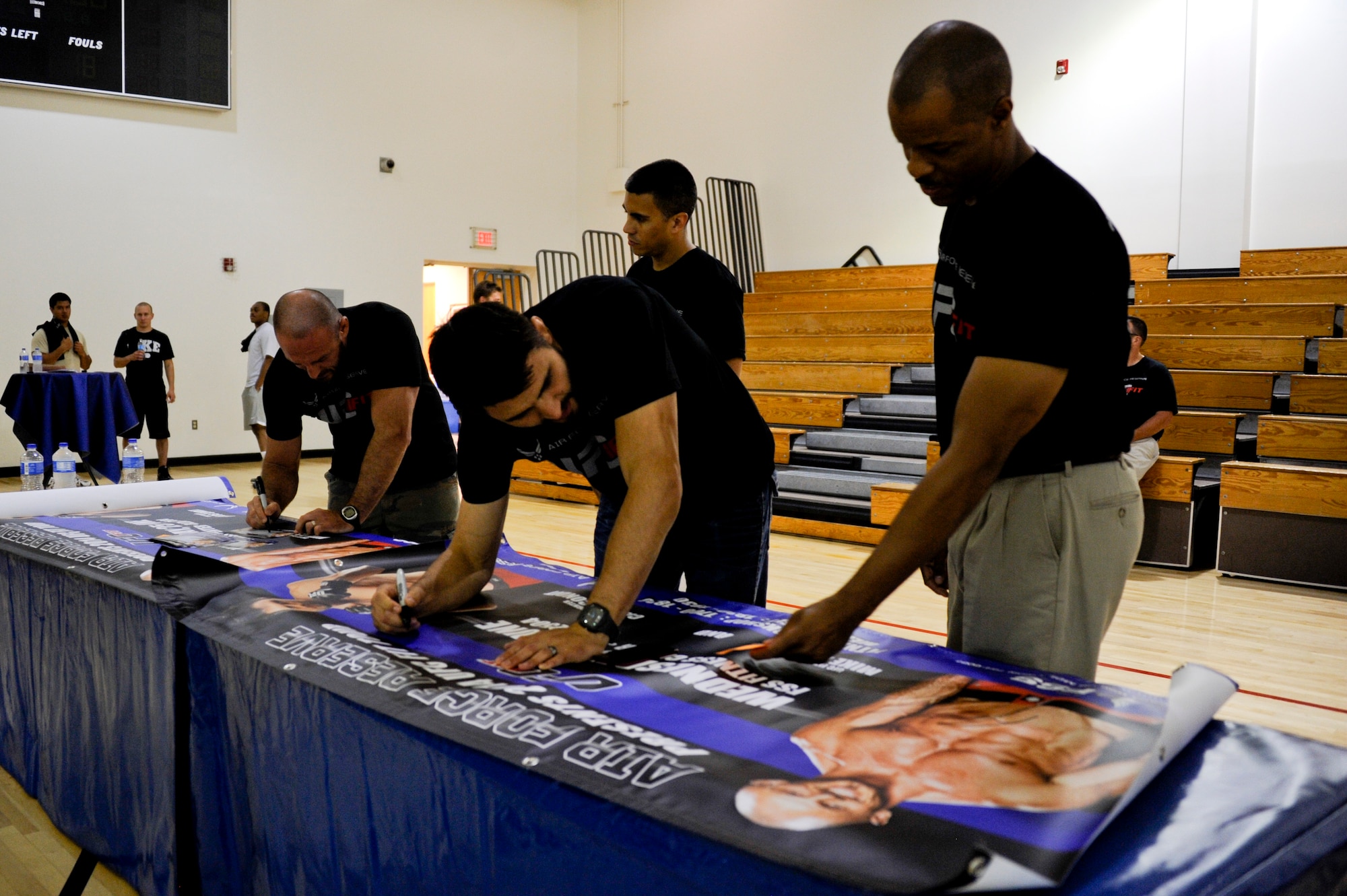 Carlos Condit, Ultimate Fighting Championship fighter, and Mike Dolce, UFC Fit coach, sign banners that were displayed to advertise the UFC Fit Tour fitness workshop June 25, 2014, at Joint Base McGuire-Dix-Lakehurst, N.J. The tour is a tool sponsored by the U.S. Air Force Reserve to promote health and fitness throughout the military. (U.S. Air Force photo by Airmen 1st Class Tara A. Williamson/Released)