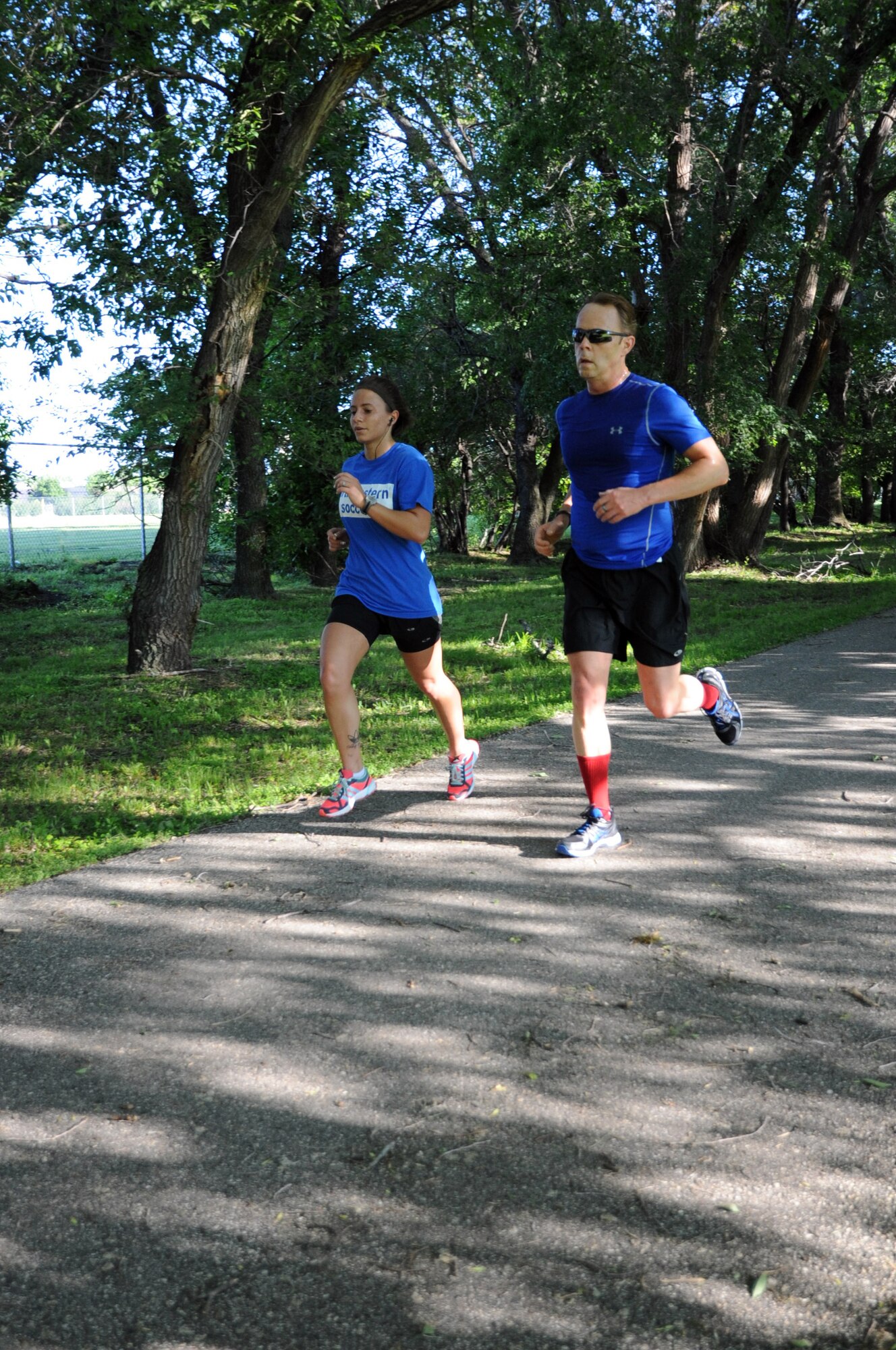 Senior Airman Olivia Minks and Neil McComsey charge down the final leg of the Independence 5K on Grand Forks Air Force Base, N.D., July 2, 2014. Minks was the first female runner to finish, with a time of 24 minutes, 23 seconds, while McComsey finished first in the males age 40-49 category with a time of 24 minutes, 26 seconds. (U.S. Air Force photo/Staff Sgt. David Dobrydney)
