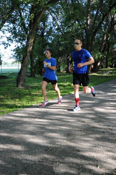 Senior Airman Olivia Minks and Neil McComsey charge down the final leg of the Independence 5K on Grand Forks Air Force Base, N.D., July 2, 2014. Minks was the first female runner to finish, with a time of 24 minutes, 23 seconds, while McComsey finished first in the males age 40-49 category with a time of 24 minutes, 26 seconds. (U.S. Air Force photo/Staff Sgt. David Dobrydney)