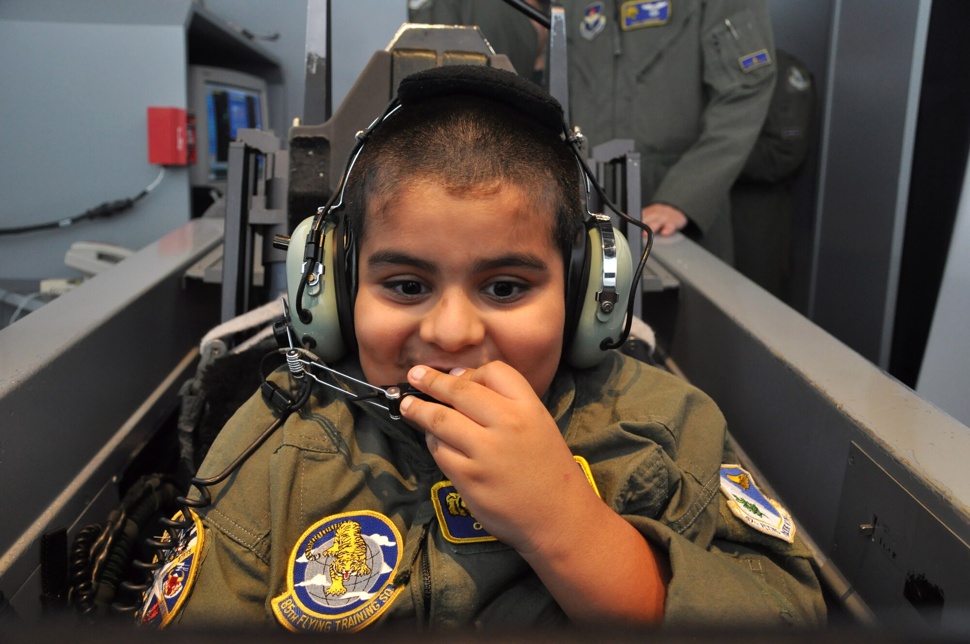Oscar Robles, Laughlin’s honorary pilot for a day, speaks into a headset microphone before taking flight in a T-6A Texan II simulator at Laughlin Air Force Base, Texas, June 27, 2014. The Pilot for a Day Program was created in 1994 to benefit local children with severe illnesses and their families and provides the child with a day completely devoted to them with the chance to experience life as an Air Force member. (U.S. Air Force photo by Airman 1st Class Ariel D. Delgado)(Released)