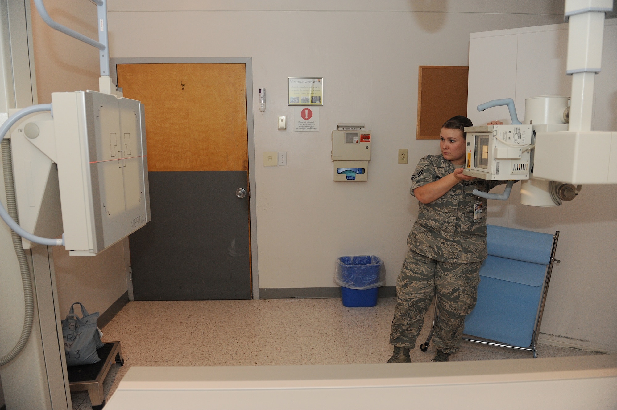 Senior Airman Casey Burch positions an X-ray tube to align with the wall bucky at Scott Air Force Base, Ill., June 3, 2014.  The tube moves up and down to coincide with a patient’s anatomy for each specific exam, including chest X-rays.  Burch is a 375th Medical Support Squadron radiology technologist.  (U.S. Air Force photo by Staff Sgt. Maria Bowman)