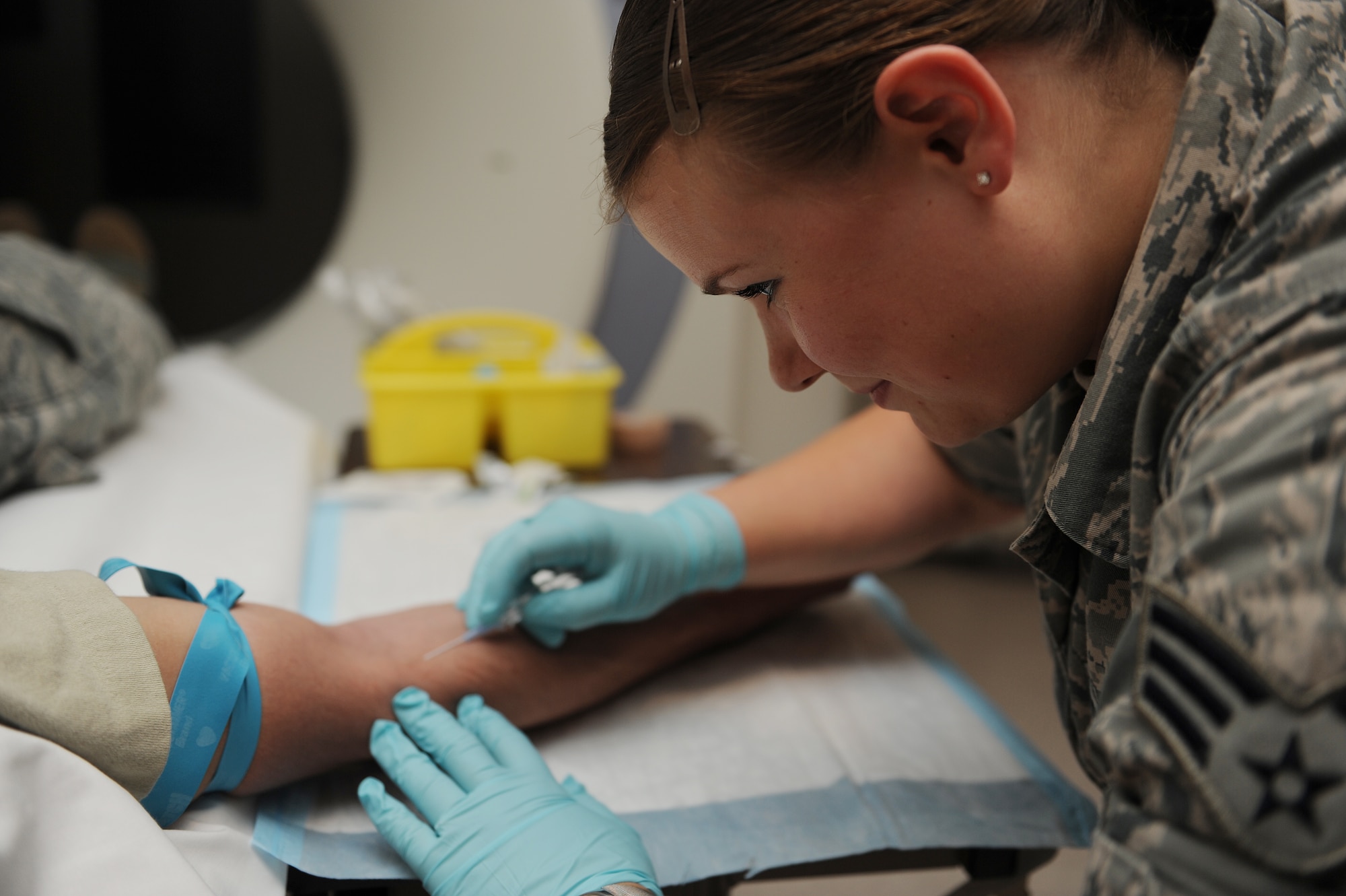Senior Airman Casey Burch prepares to insert an IV into a patient before going into the CT scan at Scott Air Force Base, Ill., June 3, 2014.  The IV delivers the contrast into the patient’s veins in order to highlight certain areas on the body when it is scanned, which makes it easier for the radiologist to see.  Burch is a 375th Medical Support Squadron radiology technologist.  (U.S. Air Force photo by Staff Sgt. Maria Bowman)