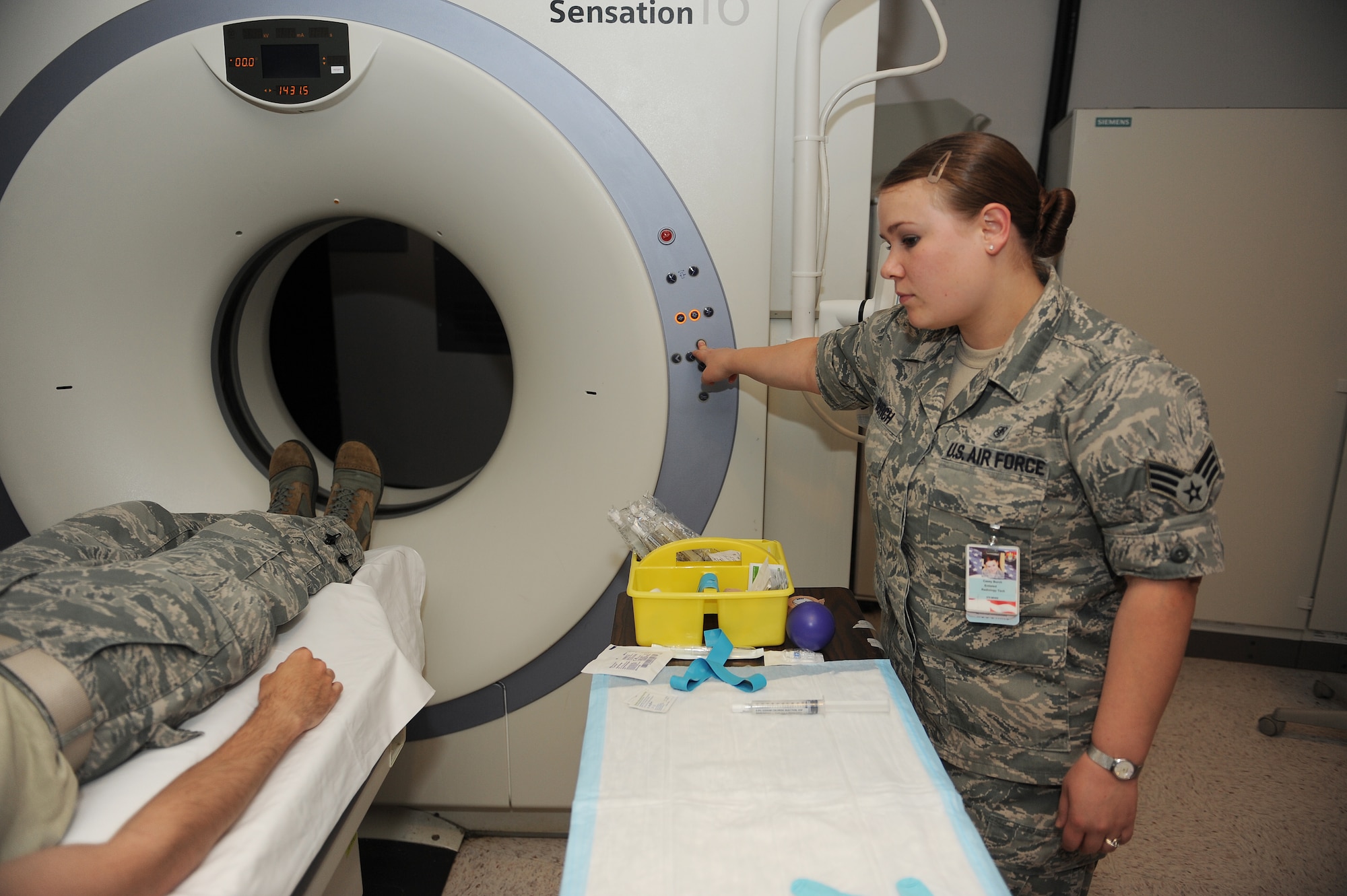Senior Airman Casey Burch raises a patient before moving him into a CT scanner at Scott Air Force Base, Ill., June 3, 2014.  A CT scan is a high-tech medical test that helps the radiologist diagnose different types of diseases.  Burch is a 375th Medical Support Squadron radiology technologist.  (U.S. Air Force photo by Staff Sgt. Maria Bowman)