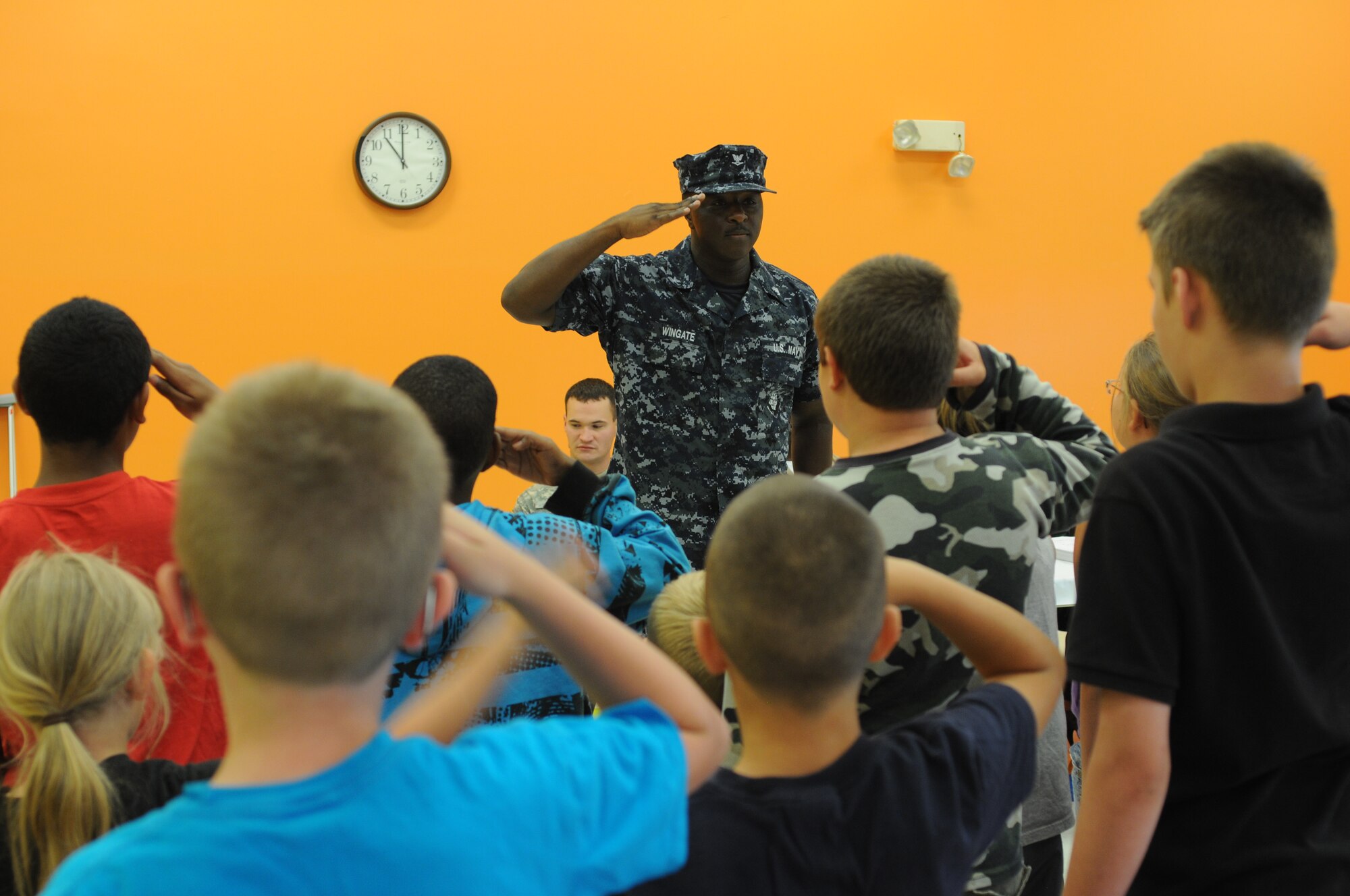 Petty Officer 3rd Class Craig Wingate, a Sailor from Navy Operational Support Center Youngstown, a tenant unit of Youngstown Air Reserve Station, instructs students at Kidz by the Riverside daycare in Warren, Ohio on how to render a proper salute June 26, 2014. Students at the daycare’s summer program crafted cards, goodie bags and posters to present to public service personnel after learning about various service professions. To receive the gifts and answer questions about their careers, the daycare invited three Airmen, a sailor and a Marine from Youngstown Air Reserve Station, along with two soldiers from Warren’s Army Recruiting Center, a local firefighter and a detective from the Trumbull County Sheriff’s office. U.S. Air Force photo/Eric M. White.