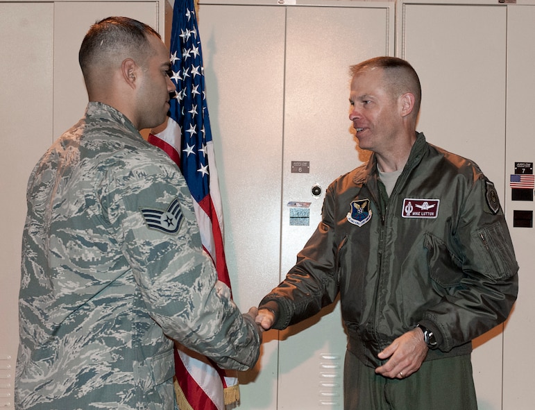 Staff Sgt. Paul Olmos III, 91st Missile Security Forces Squadron tactical response force team leader, and Senior Airman Gareck Esposito, 91st MSFS TRF sharp shooter, are coined by Col. Michael Lutton, 91st Missile Wing commander, at the TRF building on Minot Air Force Base, N.D., July 2, 2014. Olmos and Esposito recently attended training courses at Camp Guernsey, with Esposito attending the sniper course, which he graduated as both Class Leader and Distinguished Graduate; and Olmos attending the K-9 course, which he graduated top of the class. Esposito was one of five TRF Airmen to attend the sniper course and one of four to graduate. Based on historical numbers for the sniper course, an 80% graduation rate, is above average making Minot’s graduation rates of all Guernsey courses, including K-9, the highest in the 20th Air Force over the last two years. (U.S. Air Force photo/Senior Airman Stephanie Morris)