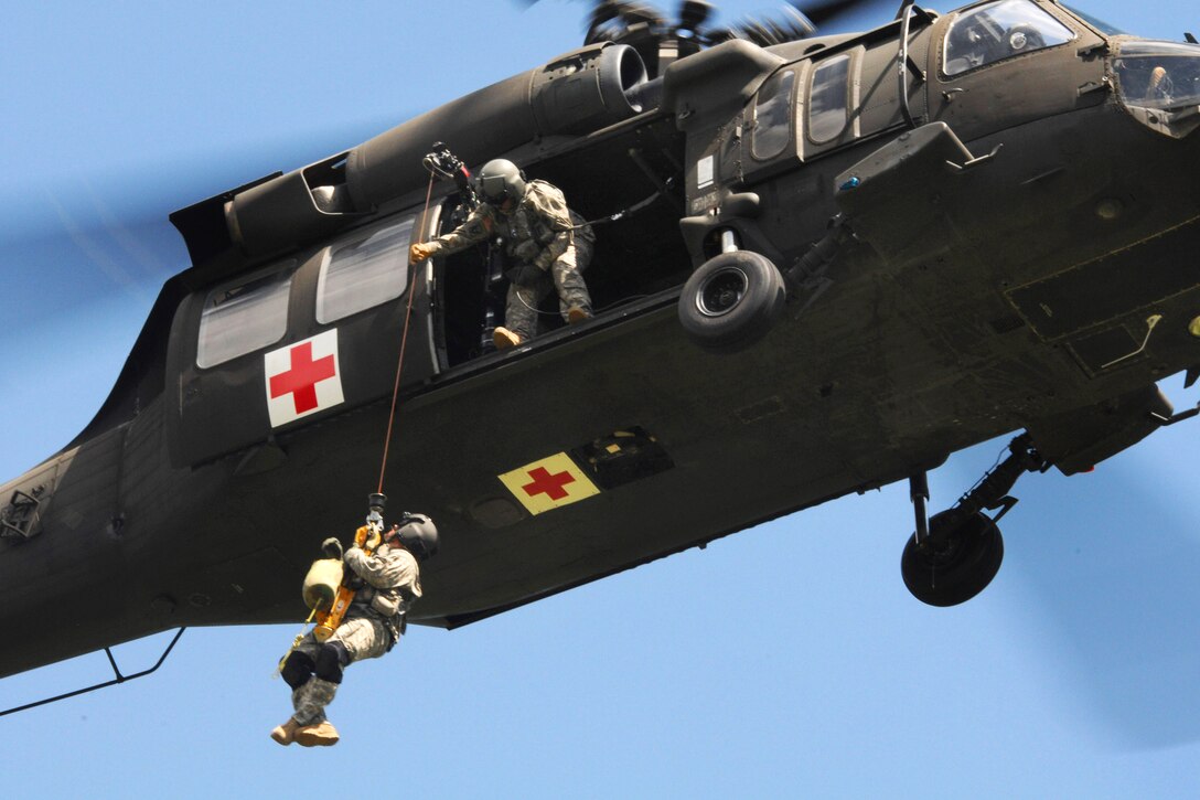 Army Sgt. Michael Severin guides the hoist from inside a UH-60 Black Hawk helicopter to bring up Army Sgt. 1st Class Greg Holland during the fourth annual Great Plains Zone Interagency Helicopter Medevac training near Pactola Reservoir, S.D., June 25, 2014. Severin is assigned to the South Dakota Army National Guard's Company C, 1st Battalion, 189th Aviation Regiment, and Holland is assigned to the Company D, 1st Battalion, 112th Aviation Regiment. 