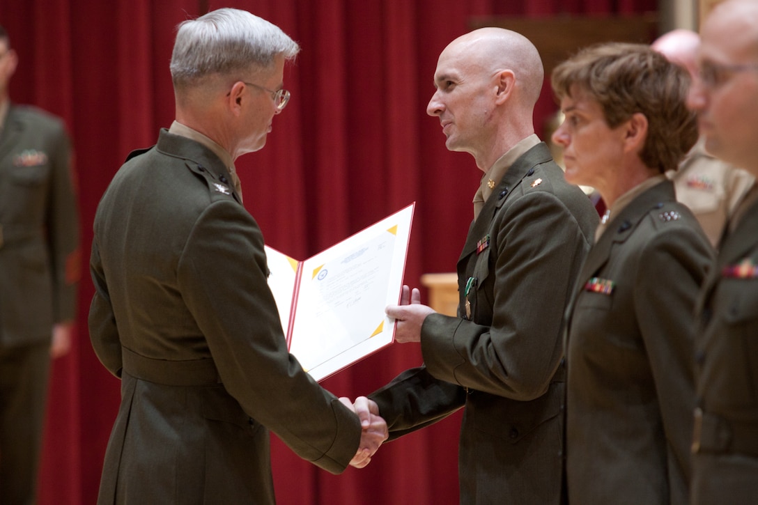 In a ceremony on July 3, 2014, at John Philip Sousa Band Hall at Marine Barracks Annex in Washington, D.C., Col. Michael J. Colburn congratulates Jason K. Fettig on his promotion to Lieutenant Colonel and on receiving the Navy Commendation Medal. (U.S. Marine Corps photo by Staff Sgt. Brian Rust/released)